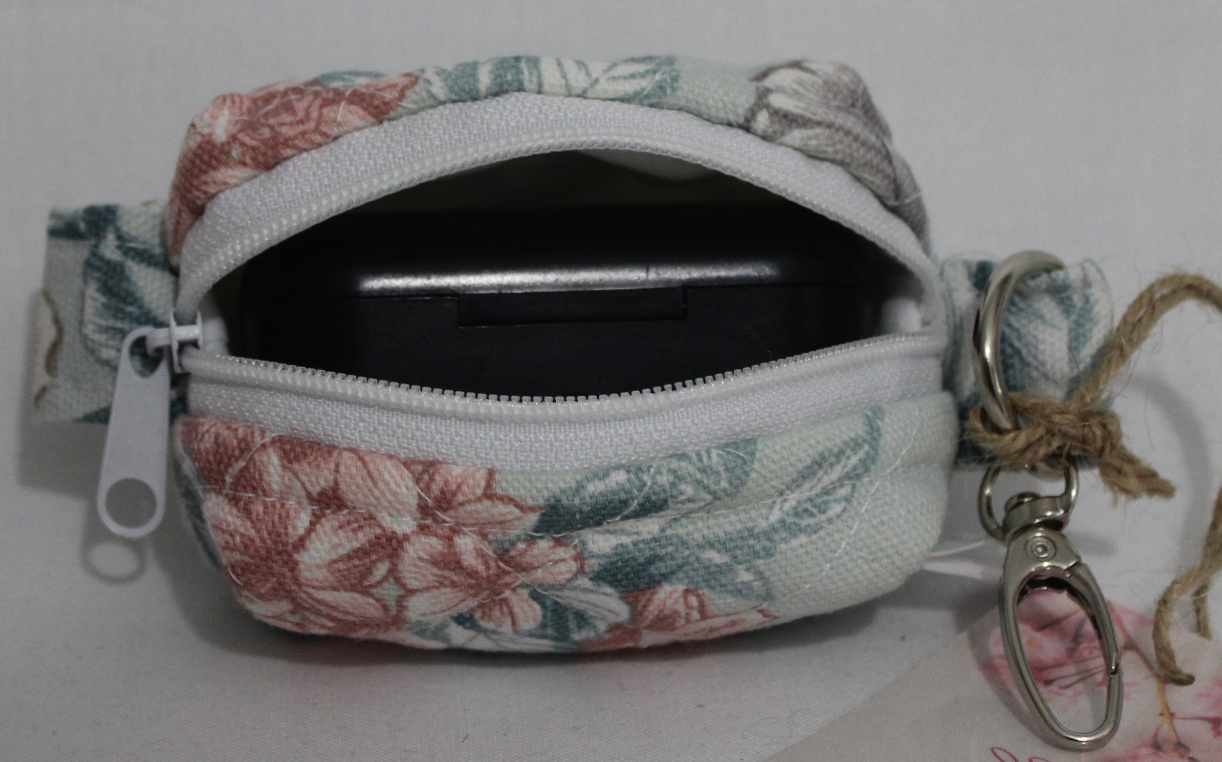 Open top view of the Joelle Bag Charm showing zip enclosure and a J Lab earbud case inserted to size reference.