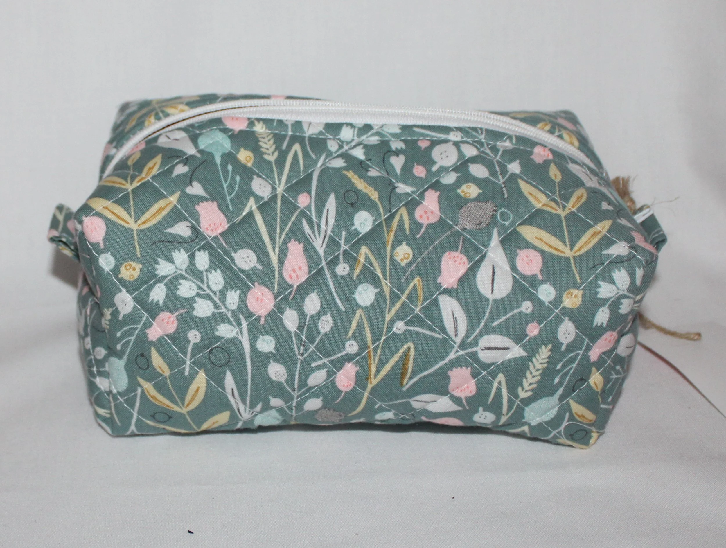 Closed side-view of the Meadow Breeze quilted travel pouch in green floral fabric.