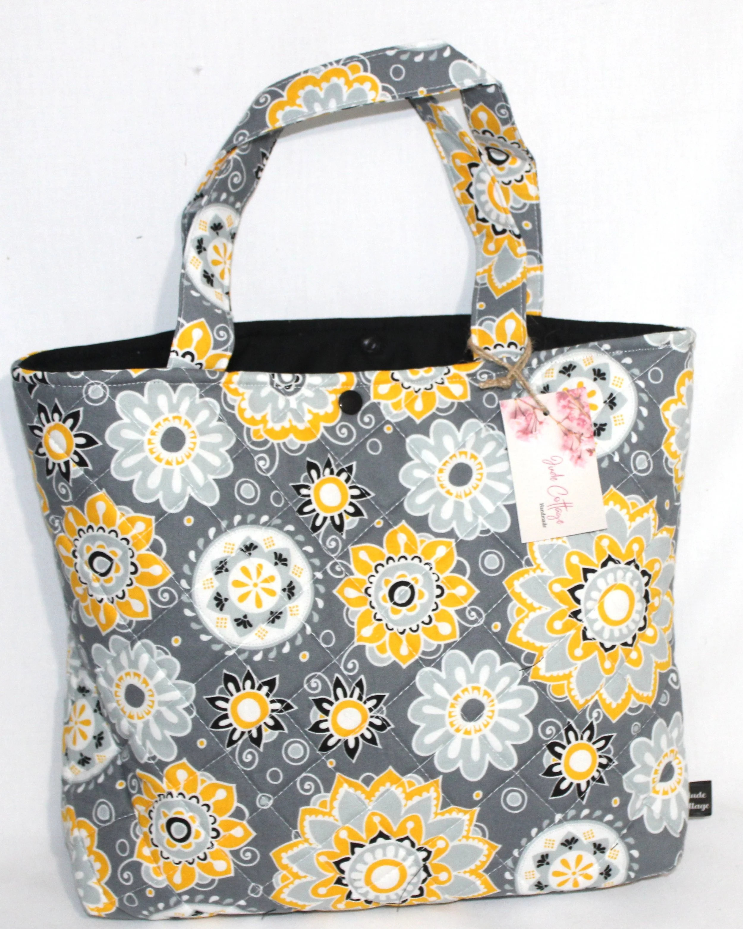 Front view of the Medallion quilted Bible sleeve with yellow, white, black, and gray floral fabric and two carry handles.