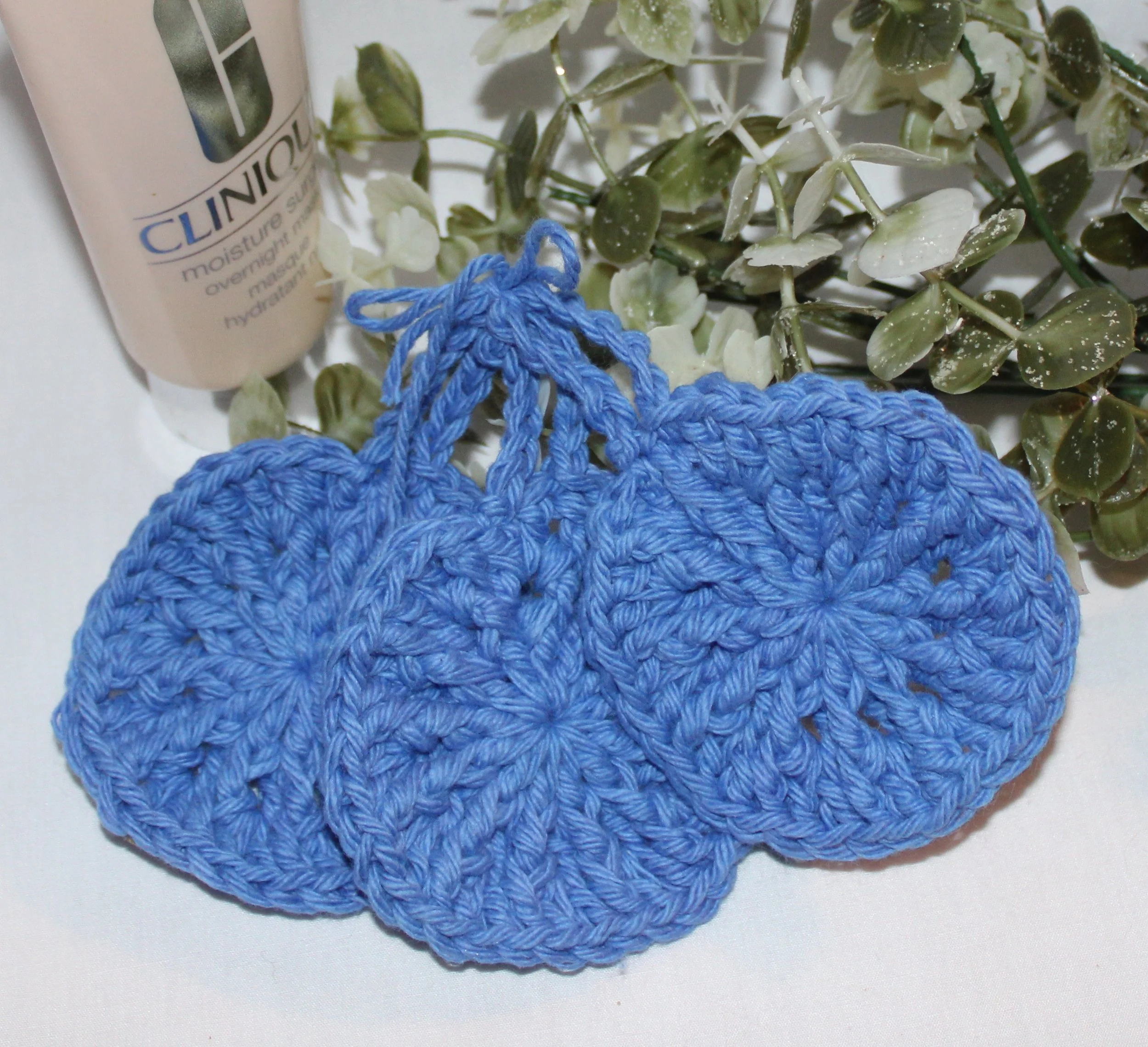 Close‑up of set of three round crocheted royal blue facial scrubbies with a textured stitch pattern