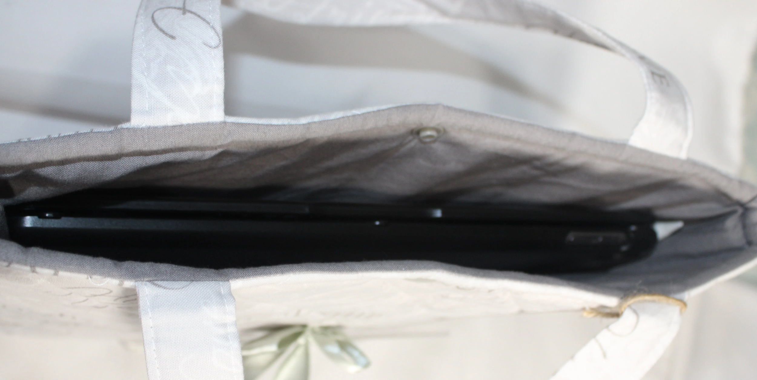 Top view of the Faith Hope Love quilted tablet and book sleeve, showing a tablet inserted and the grey lining visible.