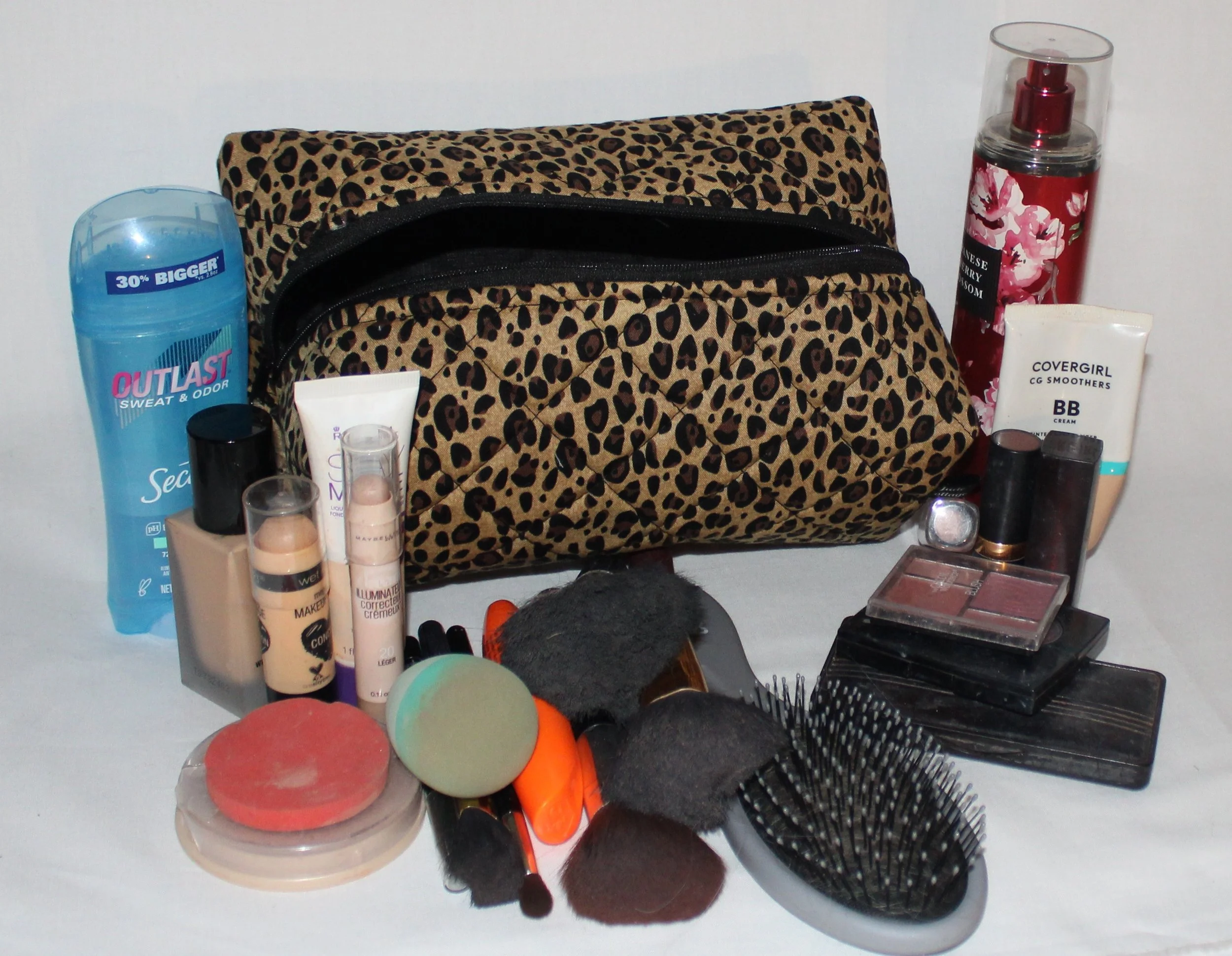 Sahara large, quilted travel pouch in cheetah print displayed with cosmetics and hygiene products arranged in front to show size.