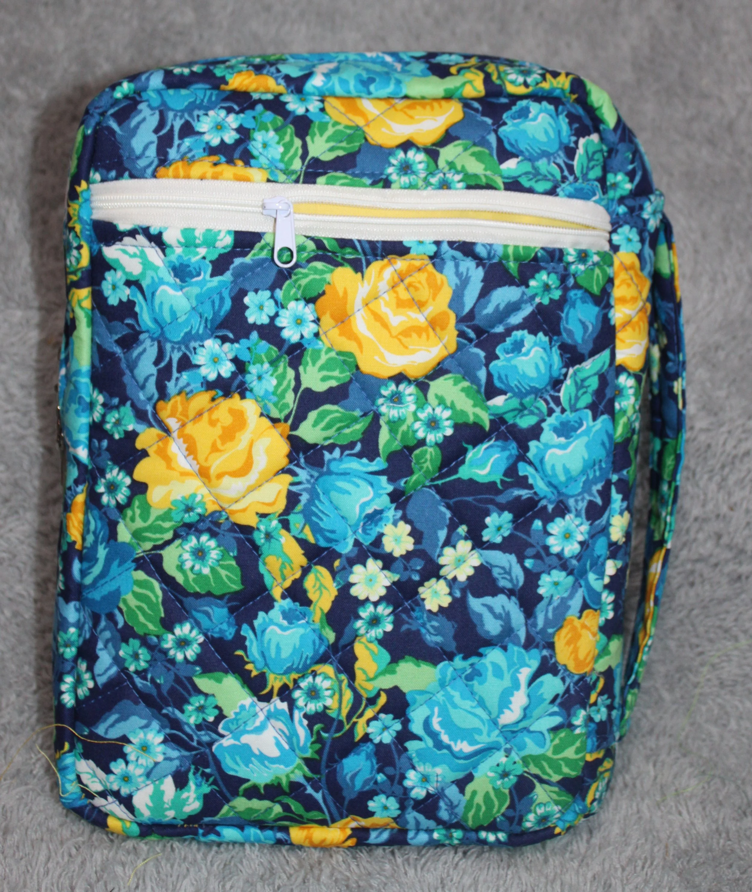 Back view of the Raisa quilted floral Bible study case in dark blue fabric with blue, white, and yellow flowers, showing the back zipper pocket.