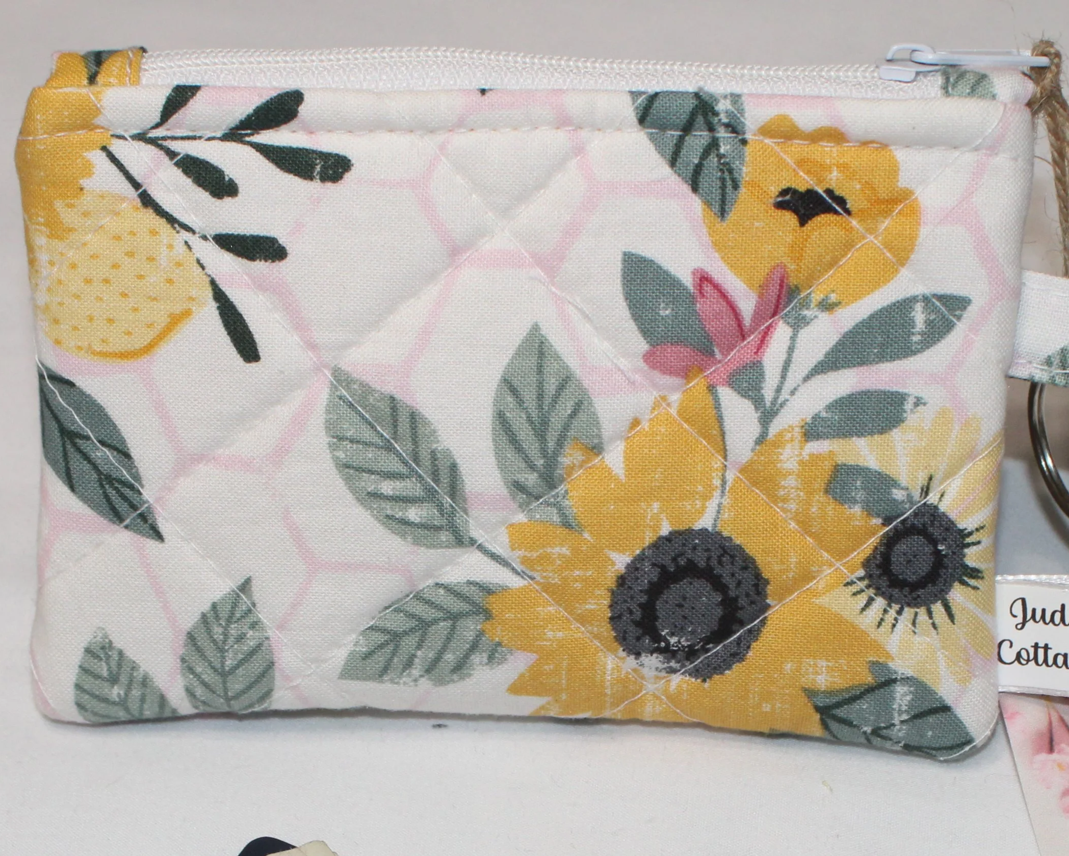 -close view of Honeycomb Sunflower quilted wallet featuring sunflowers and leaves on a white and pink geometric background.