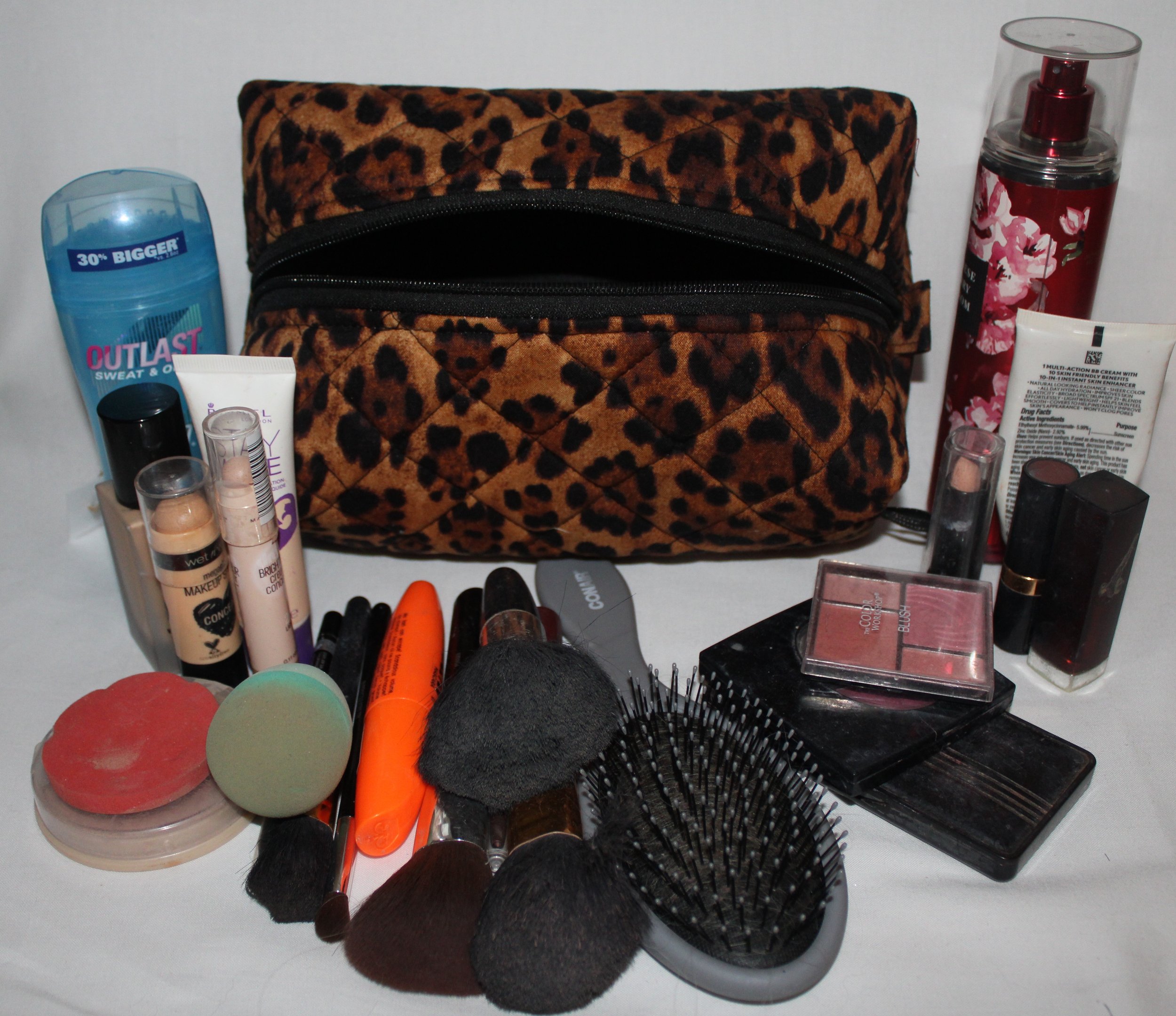 Top empty view of the small Lyra quilted travel pouch in brown and black leopard fabric with assorted cosmetics arranged around it.