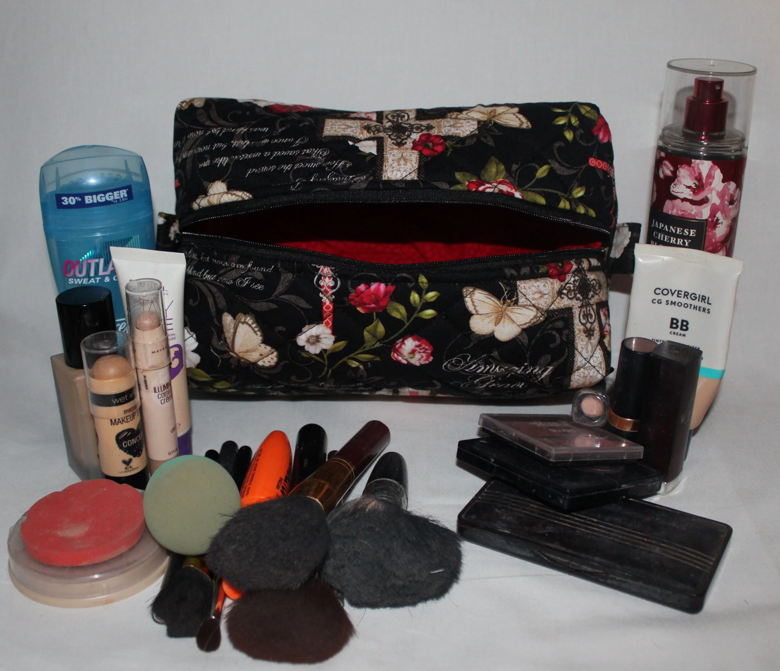 Angled top view of the large Amazing Grace floral quilted travel pouch with the open zipper showing the red interior.