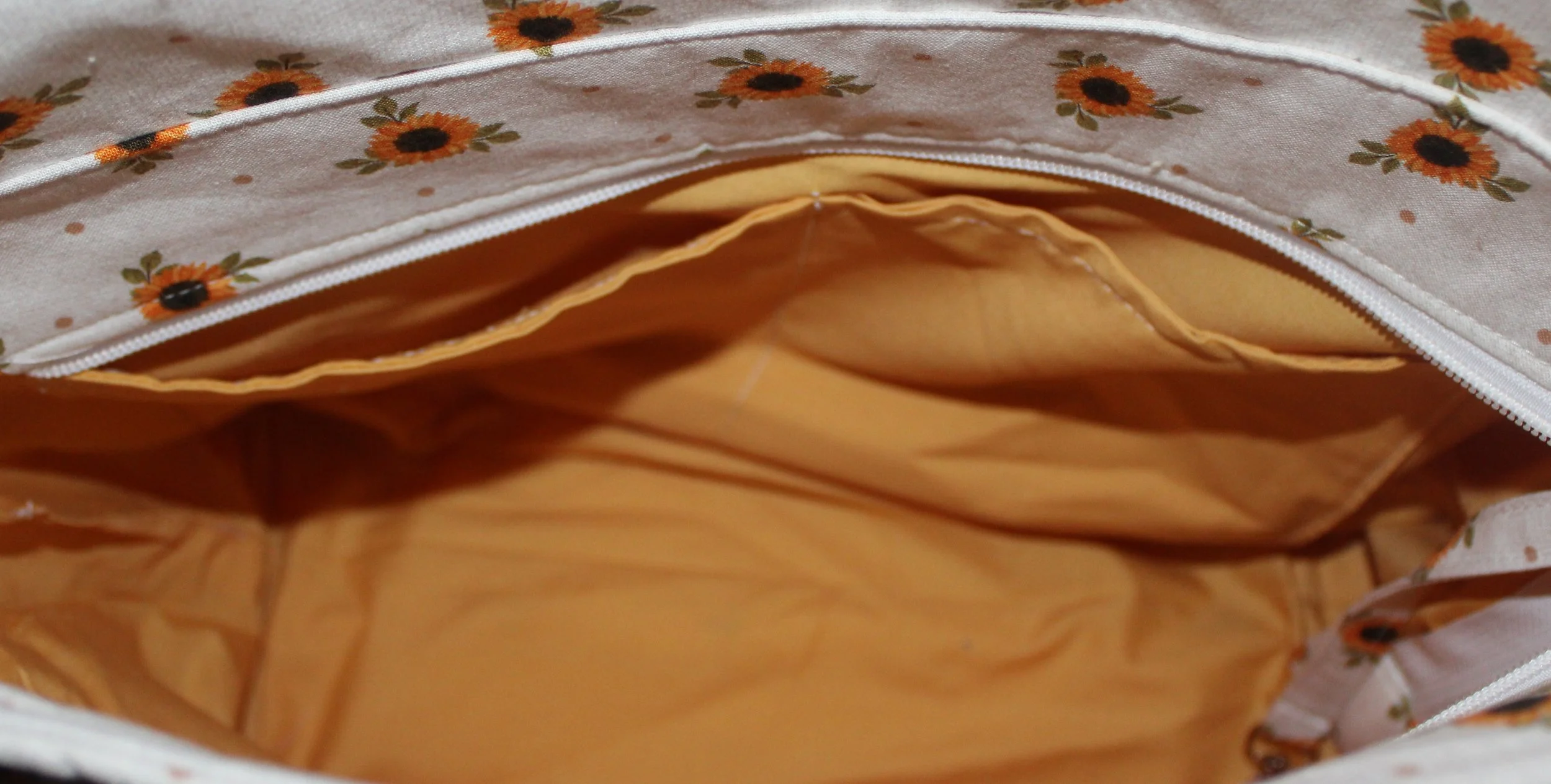 Open top view of the Sunflower Medley quilted tote in white fabric with a dainty sunflower floral pattern, showing the two inner slip pockets, and the recessed zipper panel folded open.