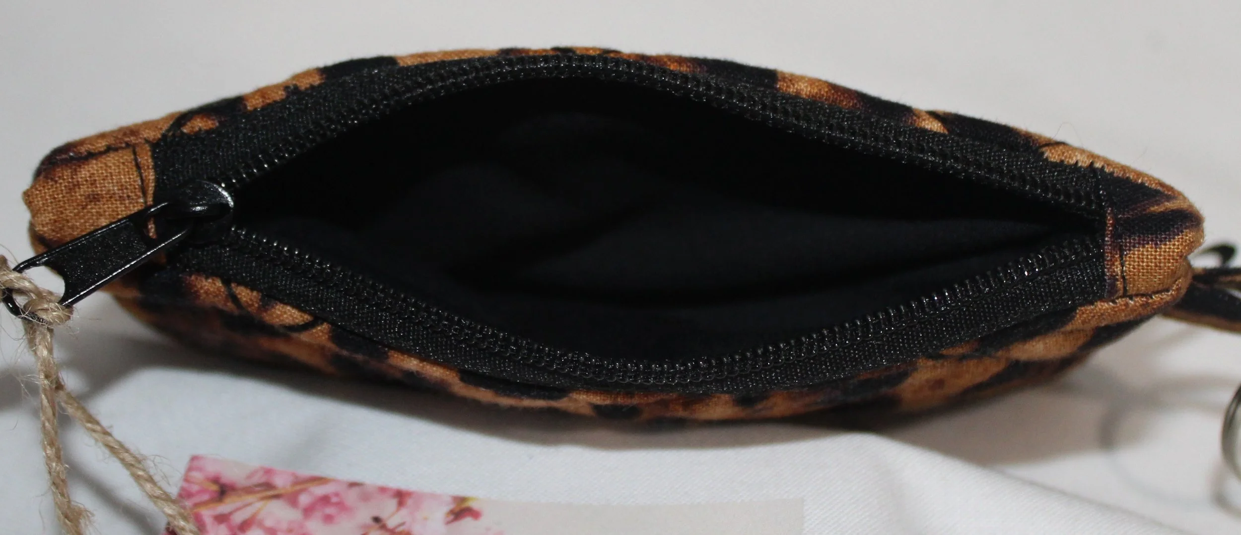 Top view of a quilted keychain wallet with Lyra leopard pattern, zipper closure, and metal key ring.