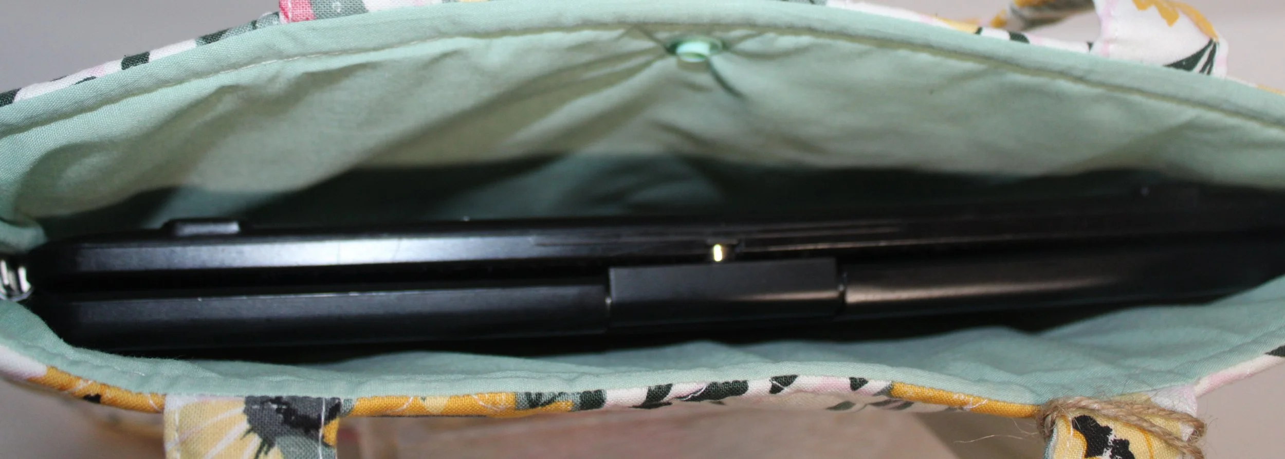 Top view of the Honeycomb Sunflower quilted tablet and book sleeve, showing a tablet inserted and the mint green lining visible.