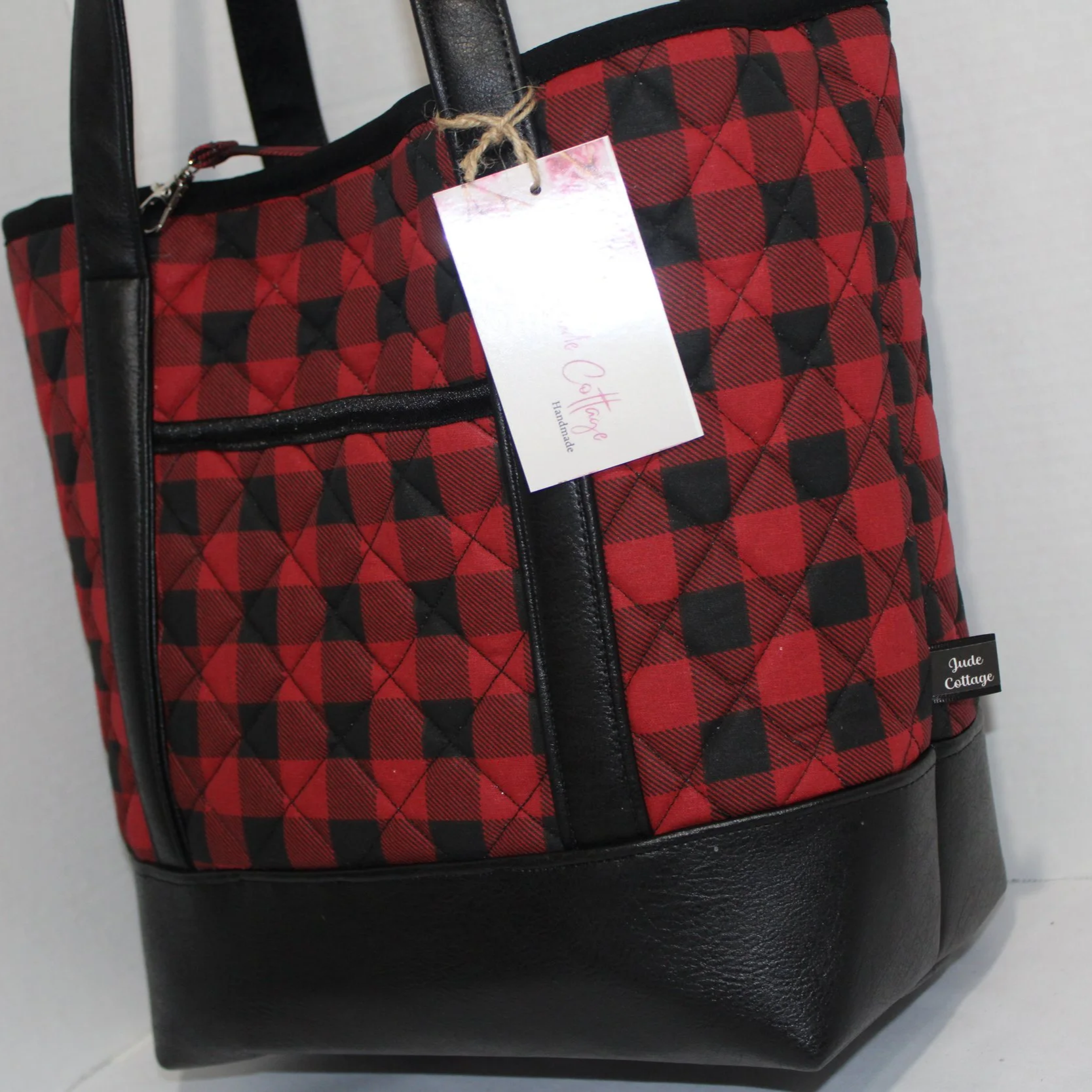 Side view of the Red Buffalo quilted tote bag featuring black faux leather with red and black buffalo print fabric.