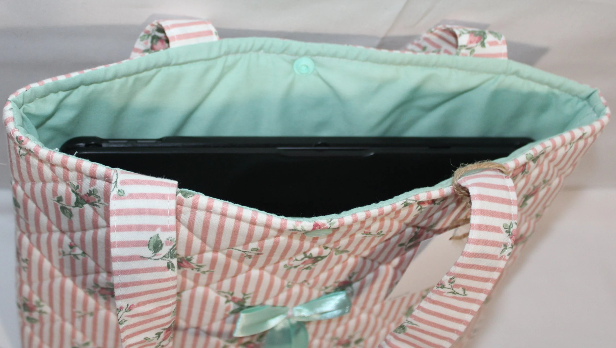 Top view of the Victoria quilted tablet and book sleeve, showing a tablet inserted and the mint green lining visible.