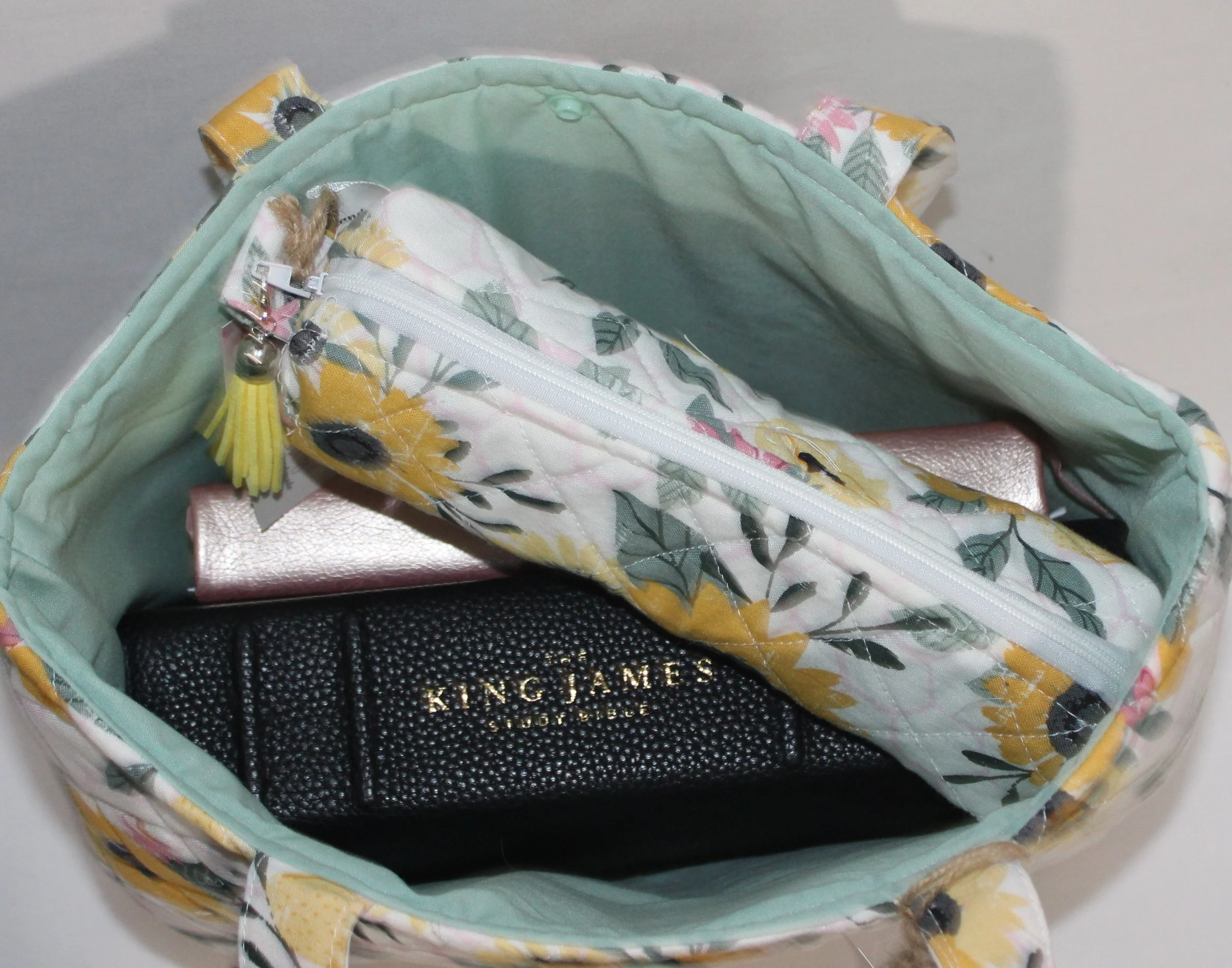 Top view of the Honeycomb Sunflower quilted Bible sleeve with a study Bible, notebook, and pencil pouch inserted to show size and intended use.