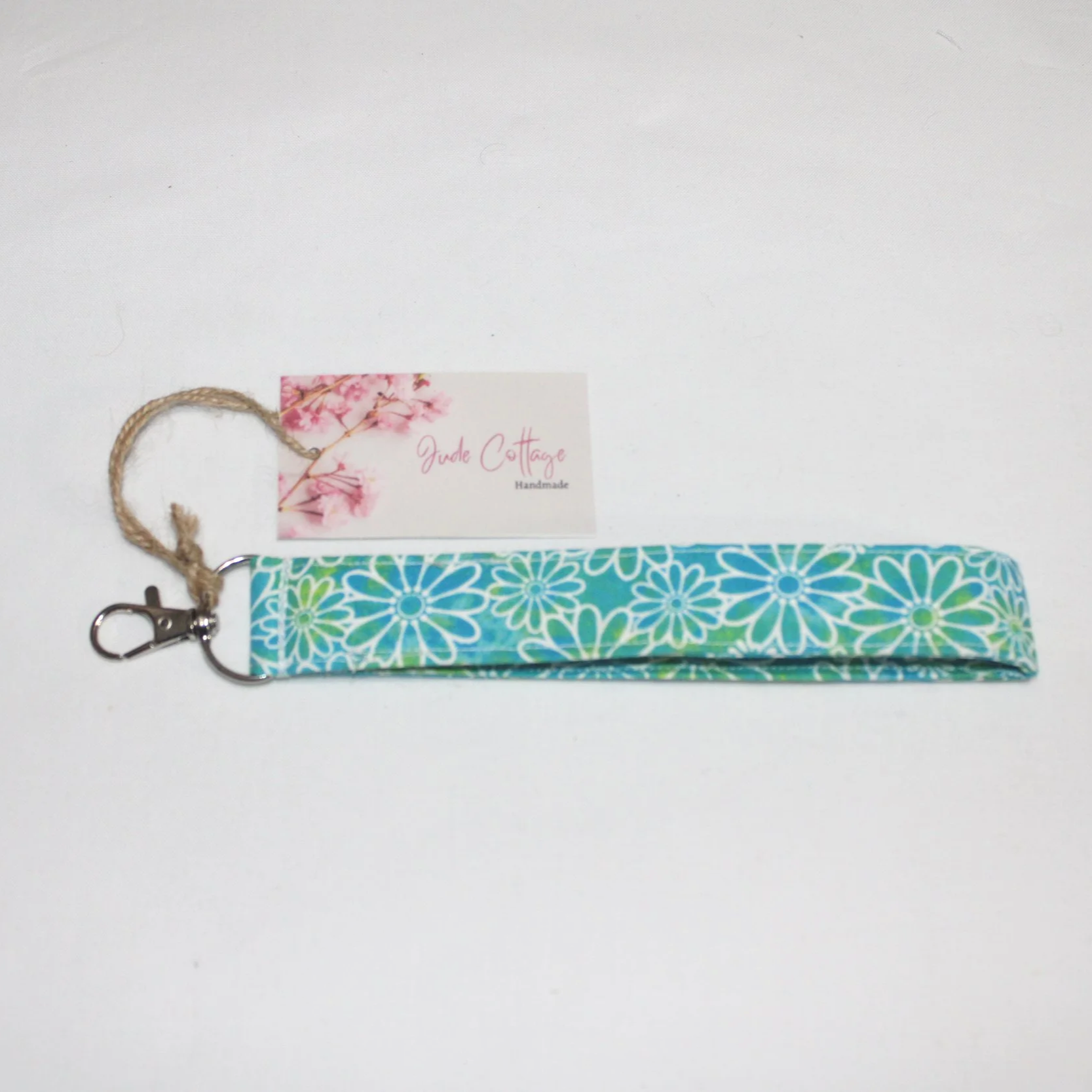 Close-up view of the Neon Daisy wristlet showing the blue and green background with white daisy print.