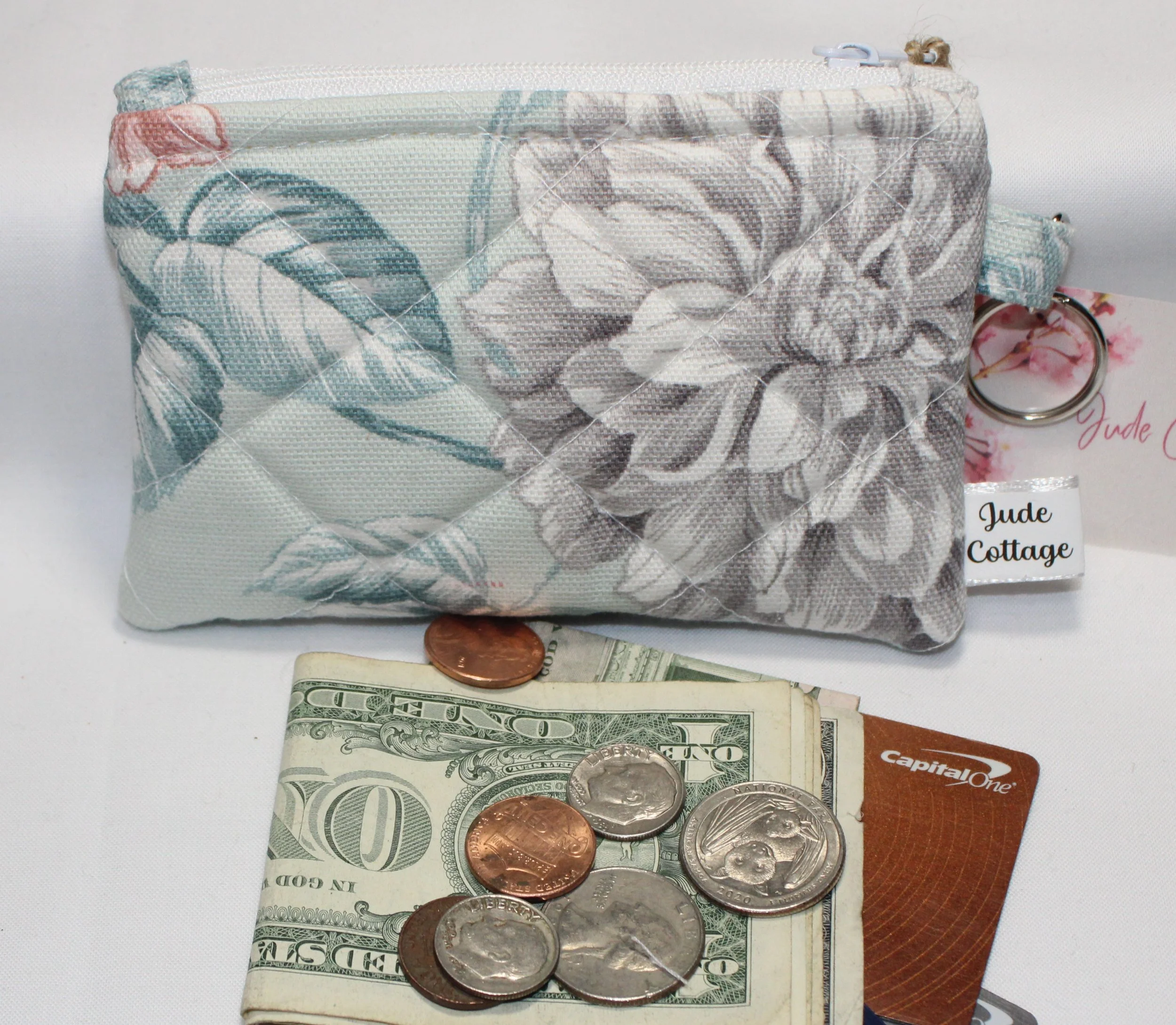Mint‑green quilted keychain wallet with magnolia floral pattern, zipper closure, and metal key ring.
