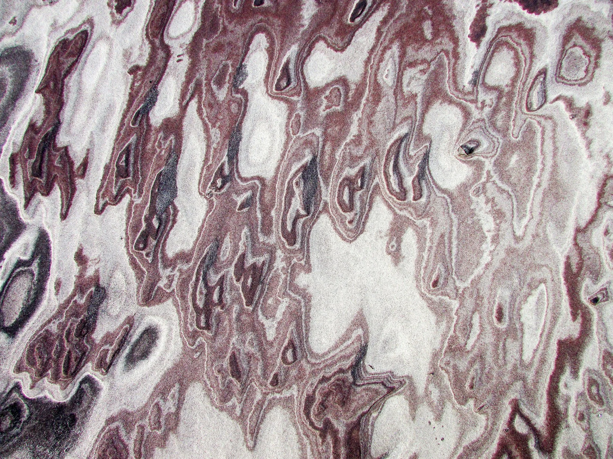 Close-up of a textured surface with intricate swirling patterns in shades of purple, pink, and white, resembling marble or mineral formations.