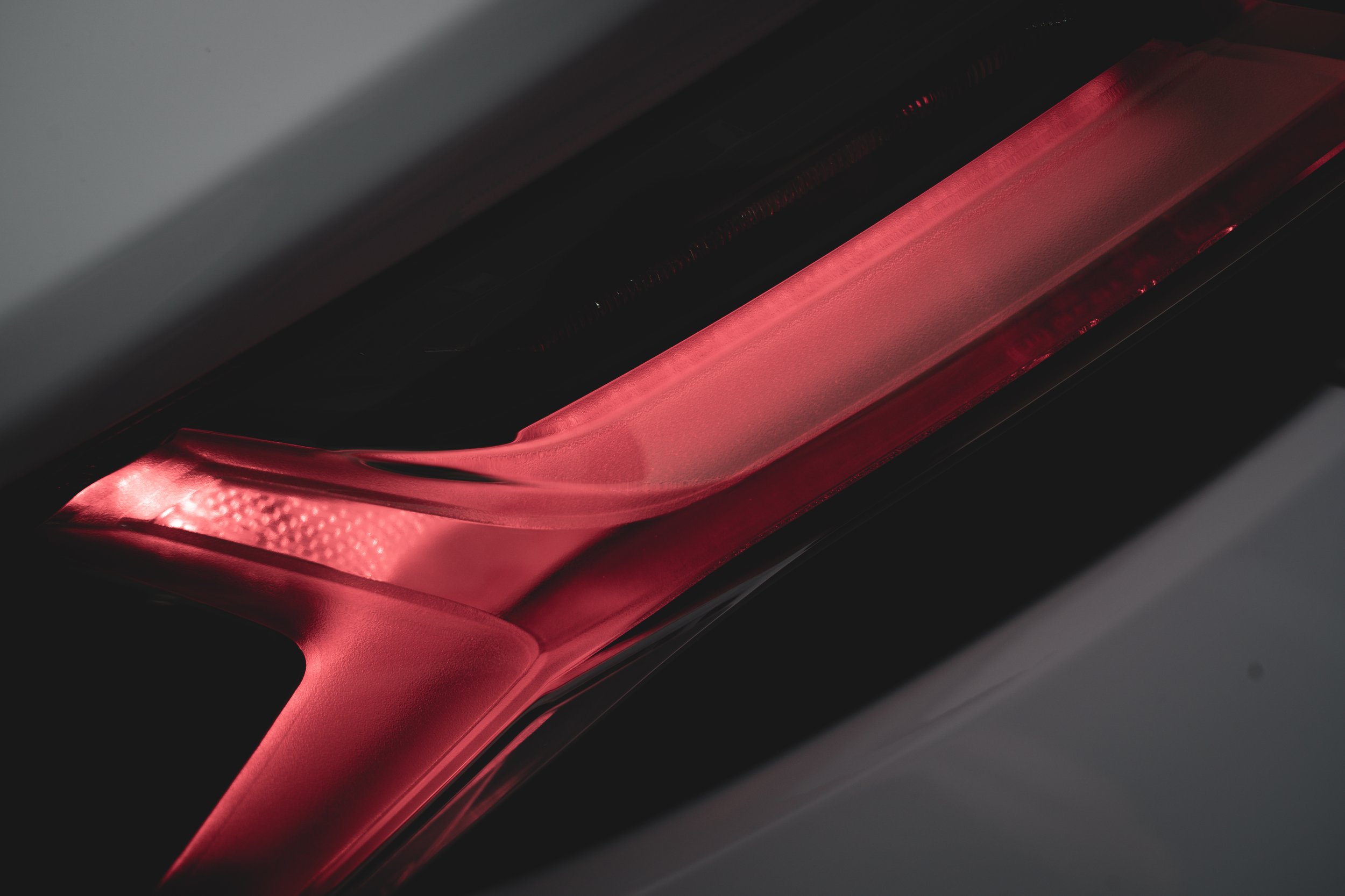 Close-up of a sleek, illuminated car tail light with a red LED design.