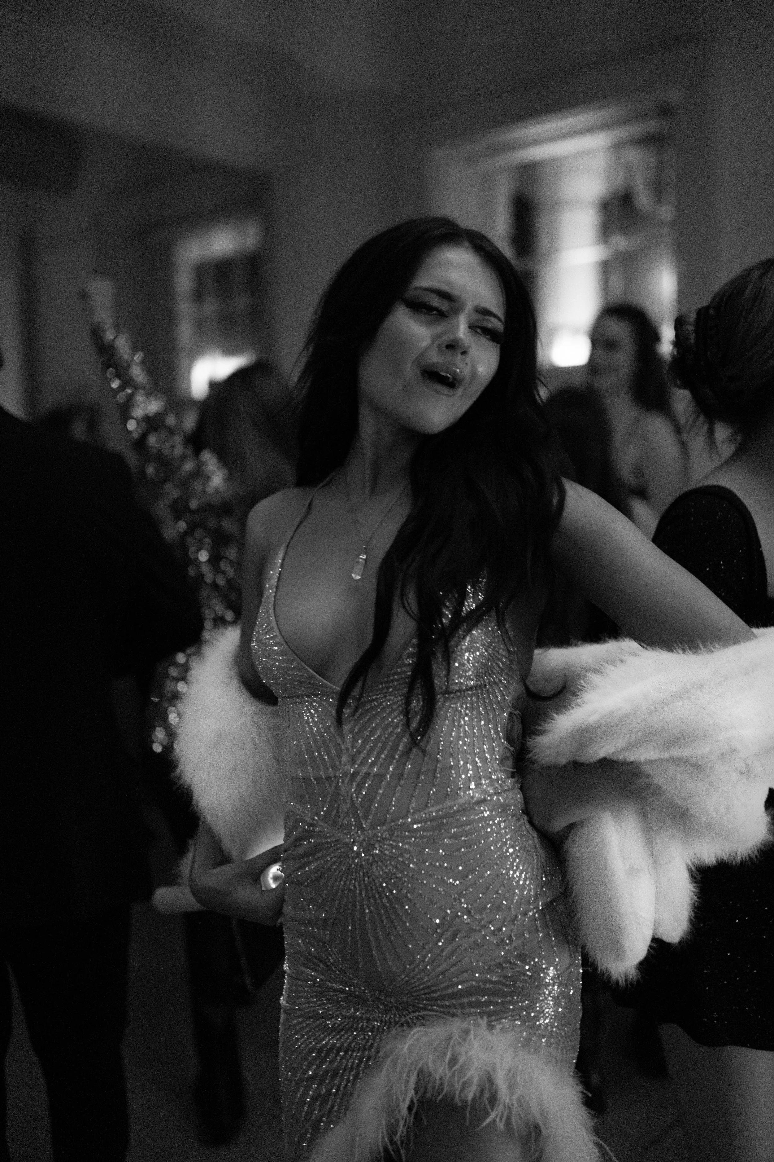 Woman in a sparkly dress and fur stole dancing at a party.