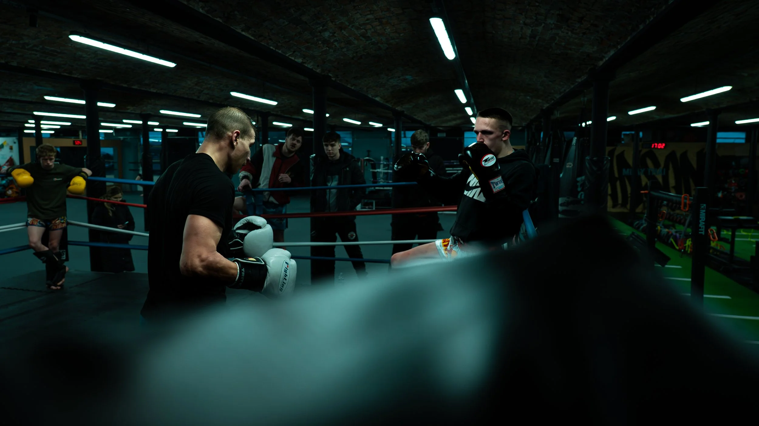 Boxers training in a boxing gym with a coach.