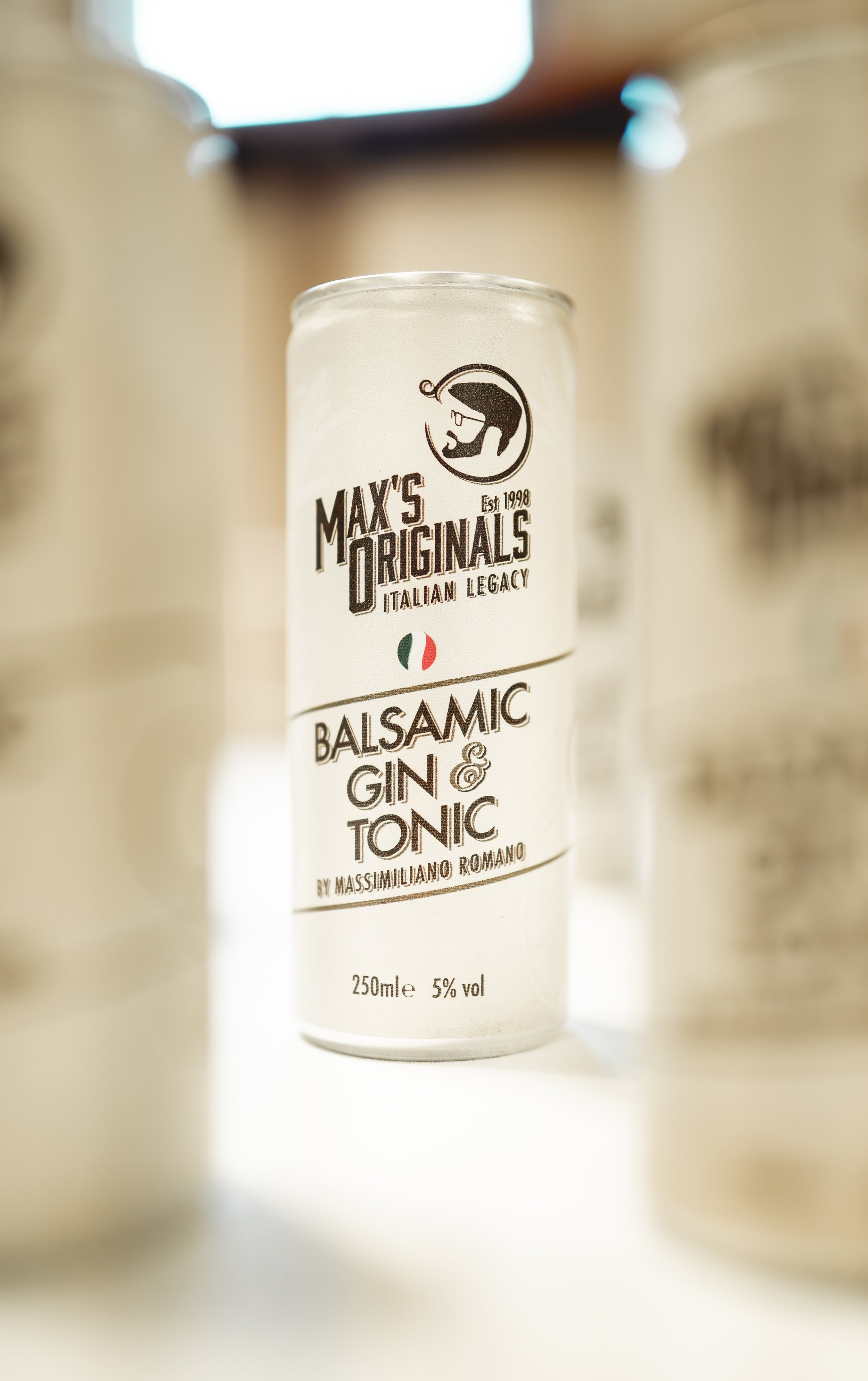 A can of Max's Originals Balsamic Gin & Tonic with Italian legacy branding, featuring a black and white logo of a person holding a glass, and text indicating it contains 250ml and 5% alcohol.