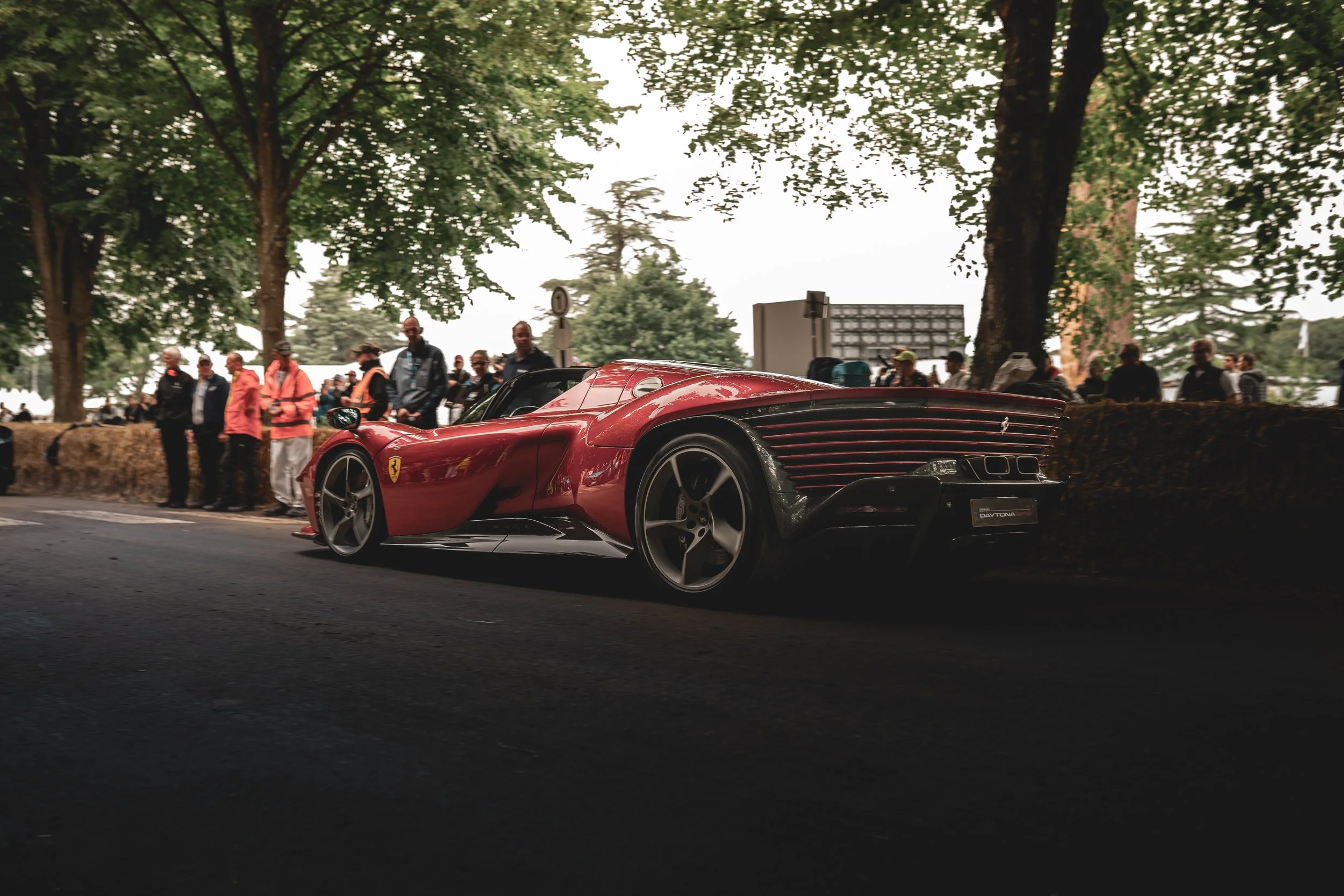 A red Ferrari LaFerrari parked on a street during a car show, with people and trees in the background.