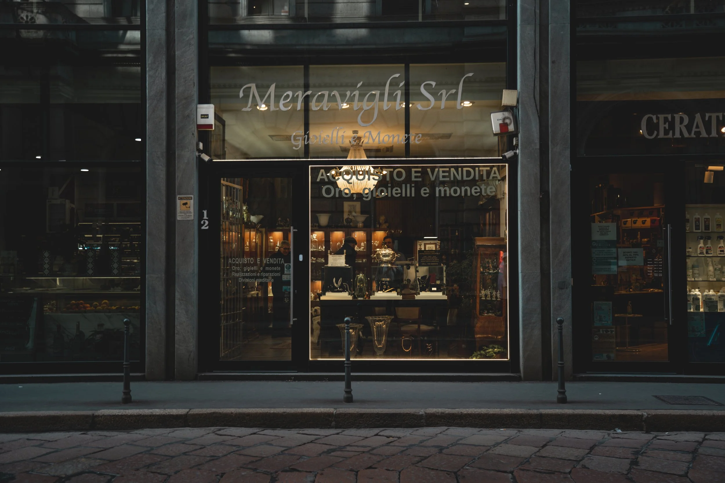  storefront with glass entrance, jewelry display, and signs in Italian for buy and sell gold, jewelry, and coins