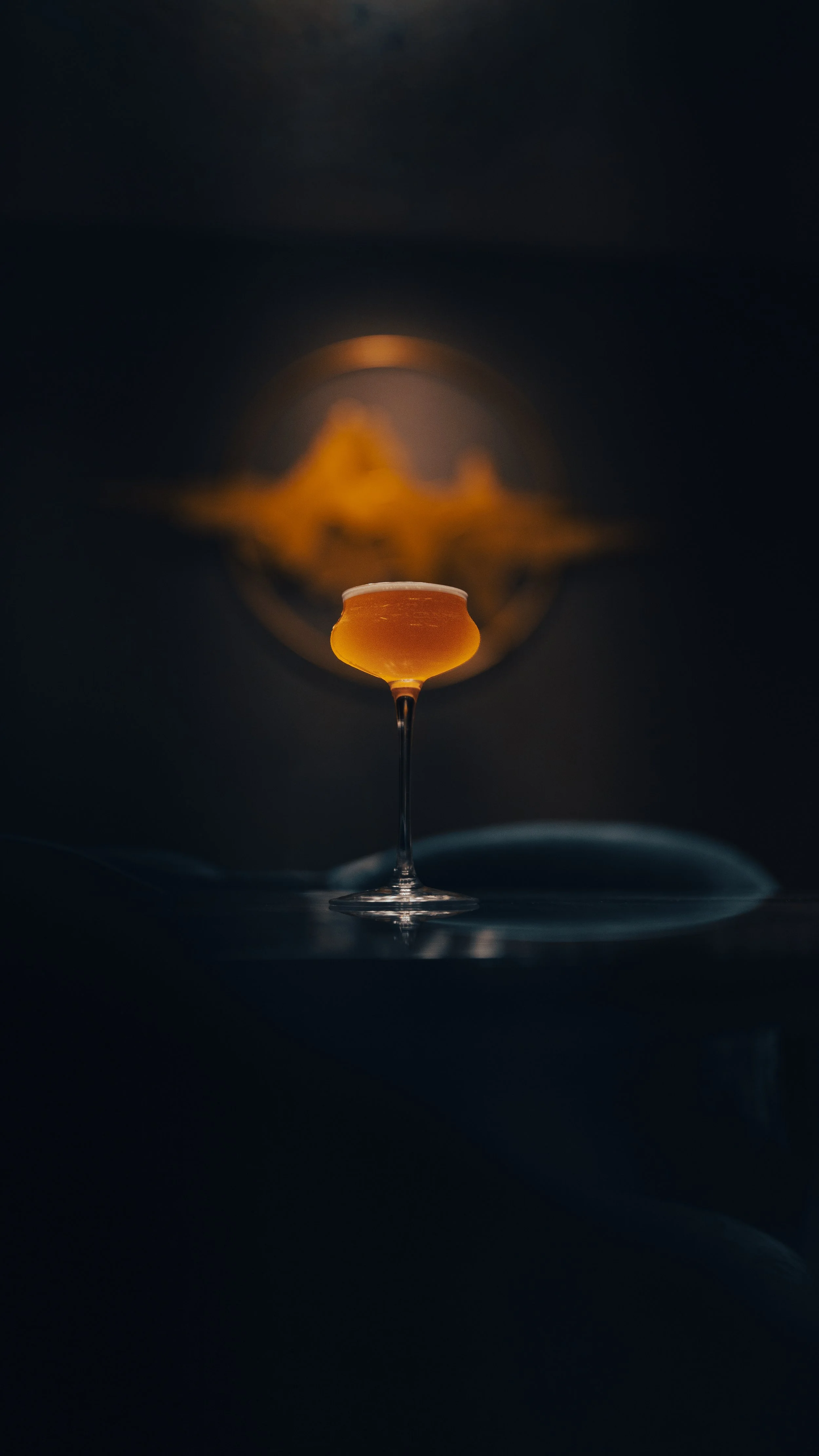 A glass of beer placed upside down on a reflective surface with a dark background.