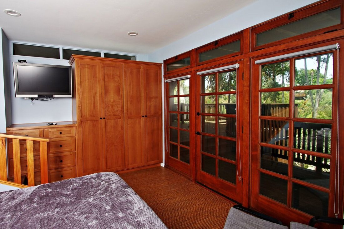 Room with wooden furniture and sliding glass doors leading outside, with trees visible through the doors.