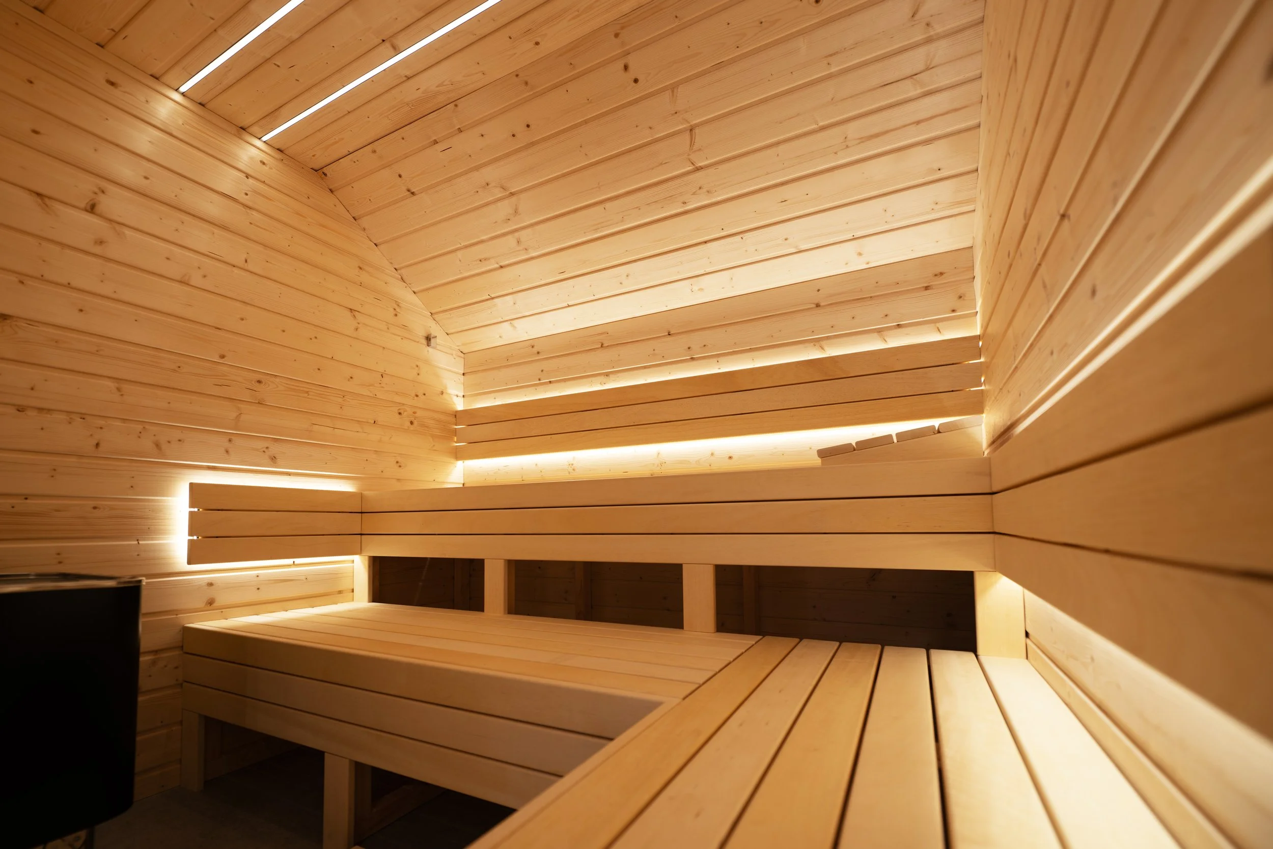 Interior of a wooden sauna with tiered wooden benches and soft lighting.