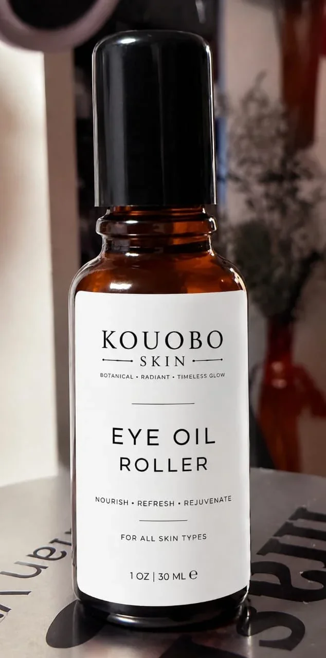 A small amber glass bottle with a black cap labeled 'Koubo Skin Eye Oil Roller,' indicating it is for nourishing, refreshing, and rejuvenating the eye area, suitable for all skin types, with a 1 oz (30 ml) capacity.