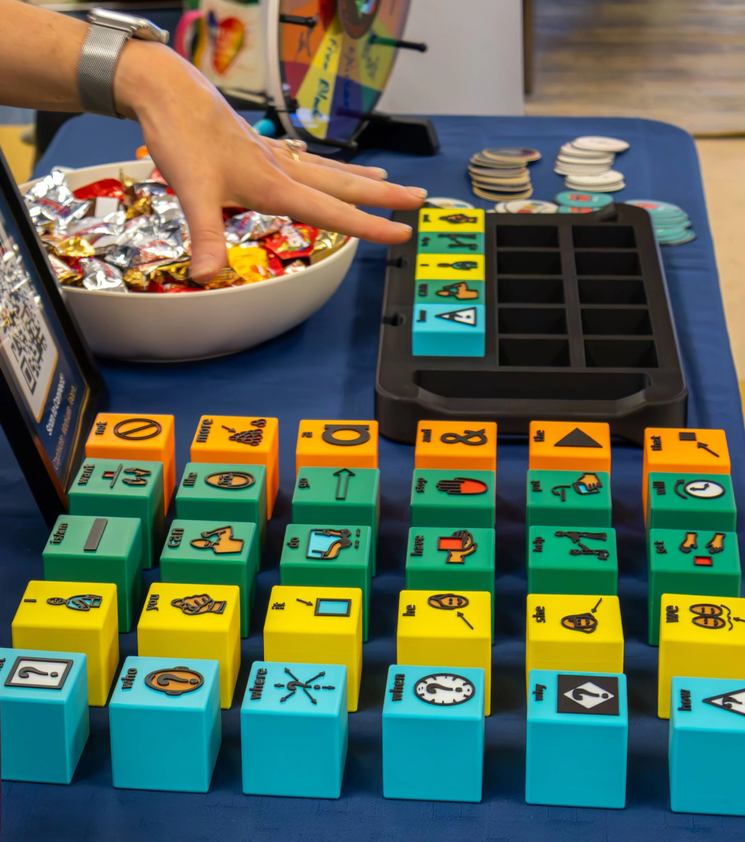 Colorful tactile AAC blocks lined up in a sentence-building storage tray on the Tactile Voices booth table at CSHA 2026