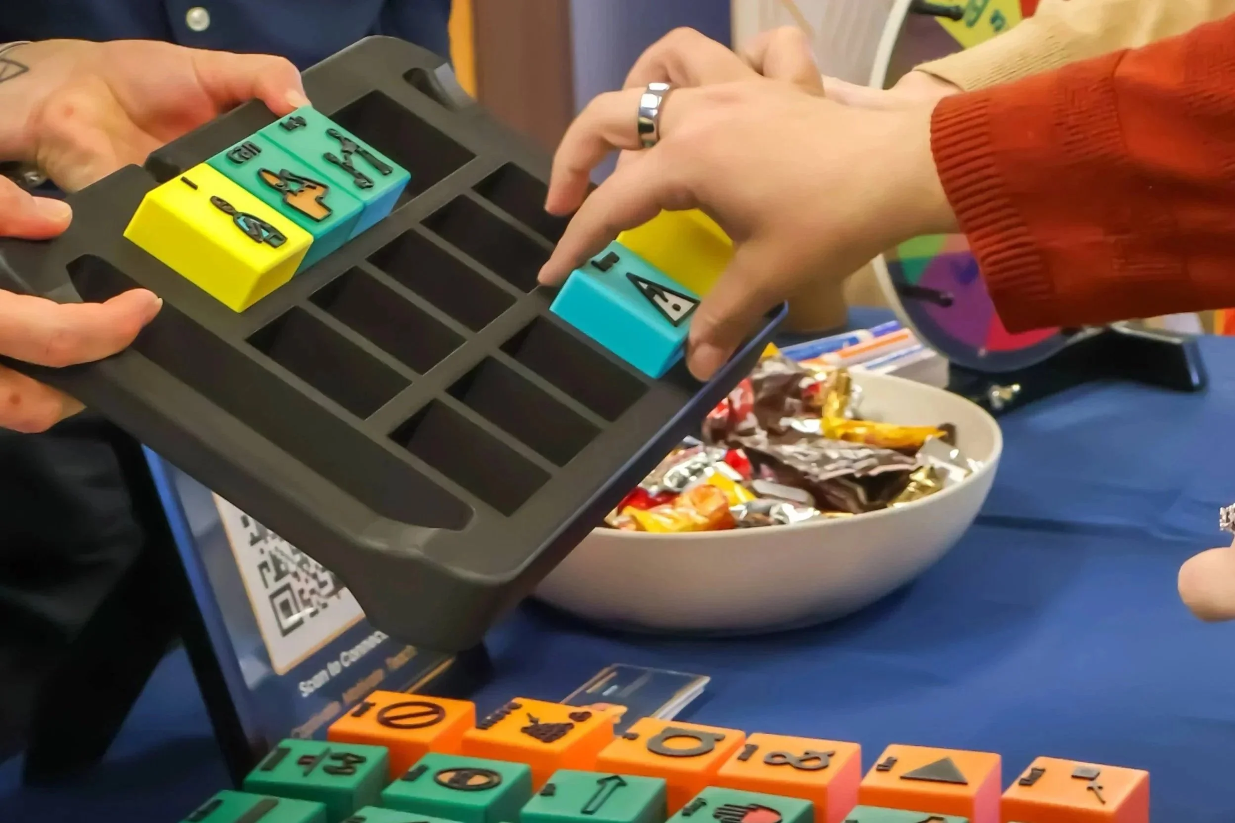 Hands sorting colorful Tactile Voices AAC blocks into a storage tray during a demo at CSHA 2026