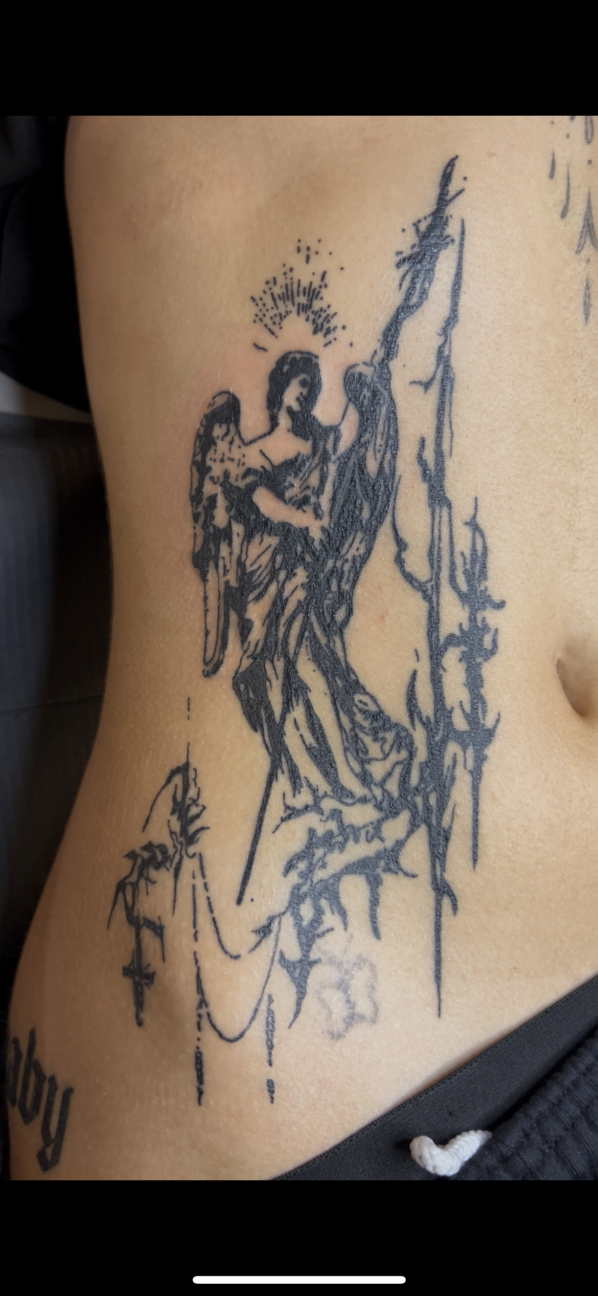 Tattoo of an angel praying, with detailed wings and a halo, on person's side