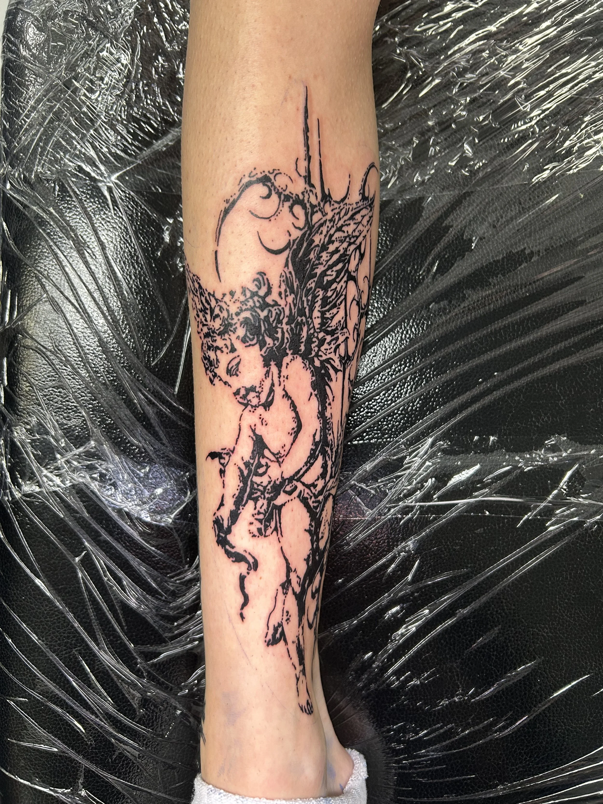 Tattoo of a fairy with wings, sitting on a branch, on a person's forearm.