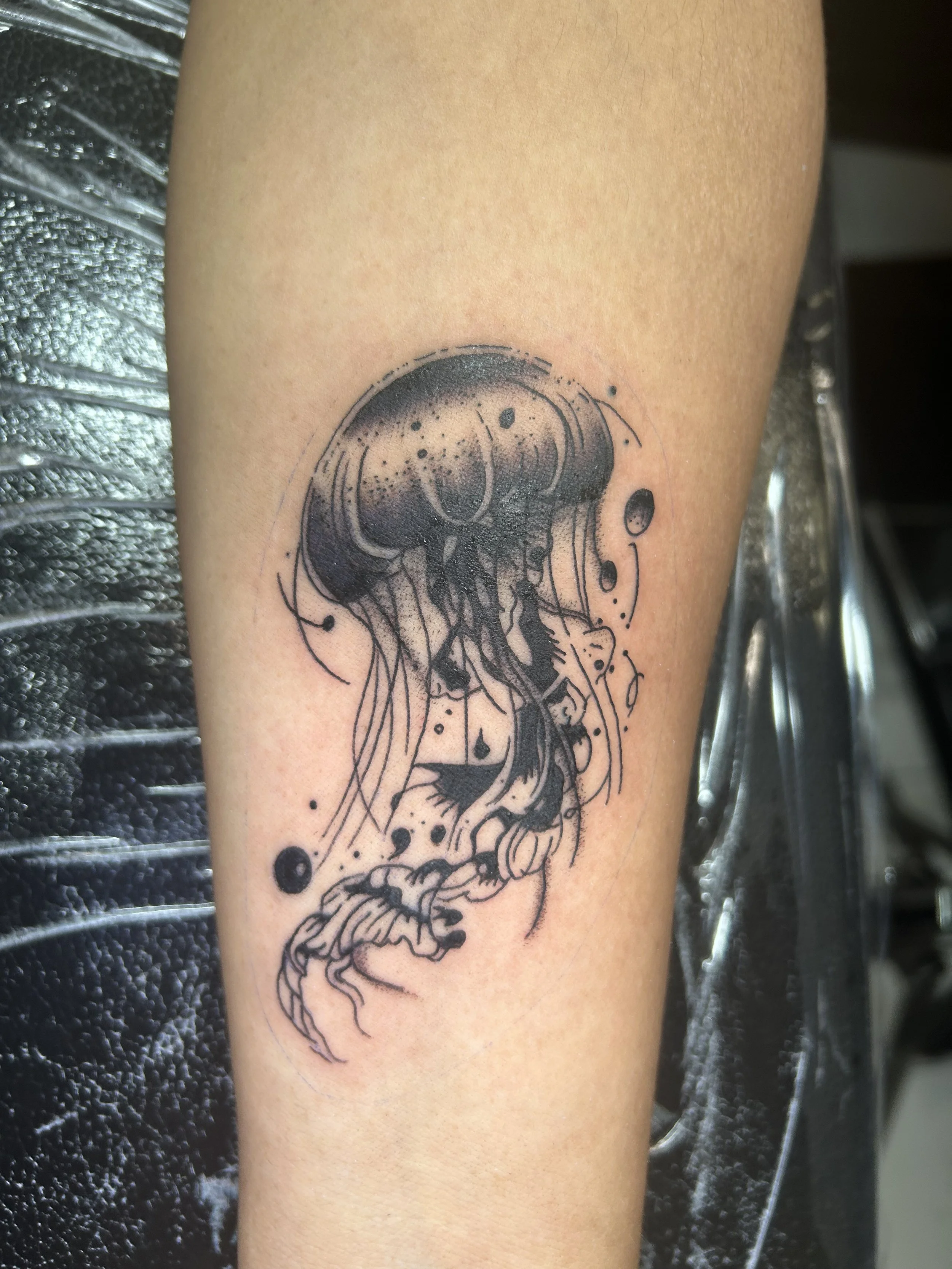 Black and gray jellyfish tattoo on person's arm.