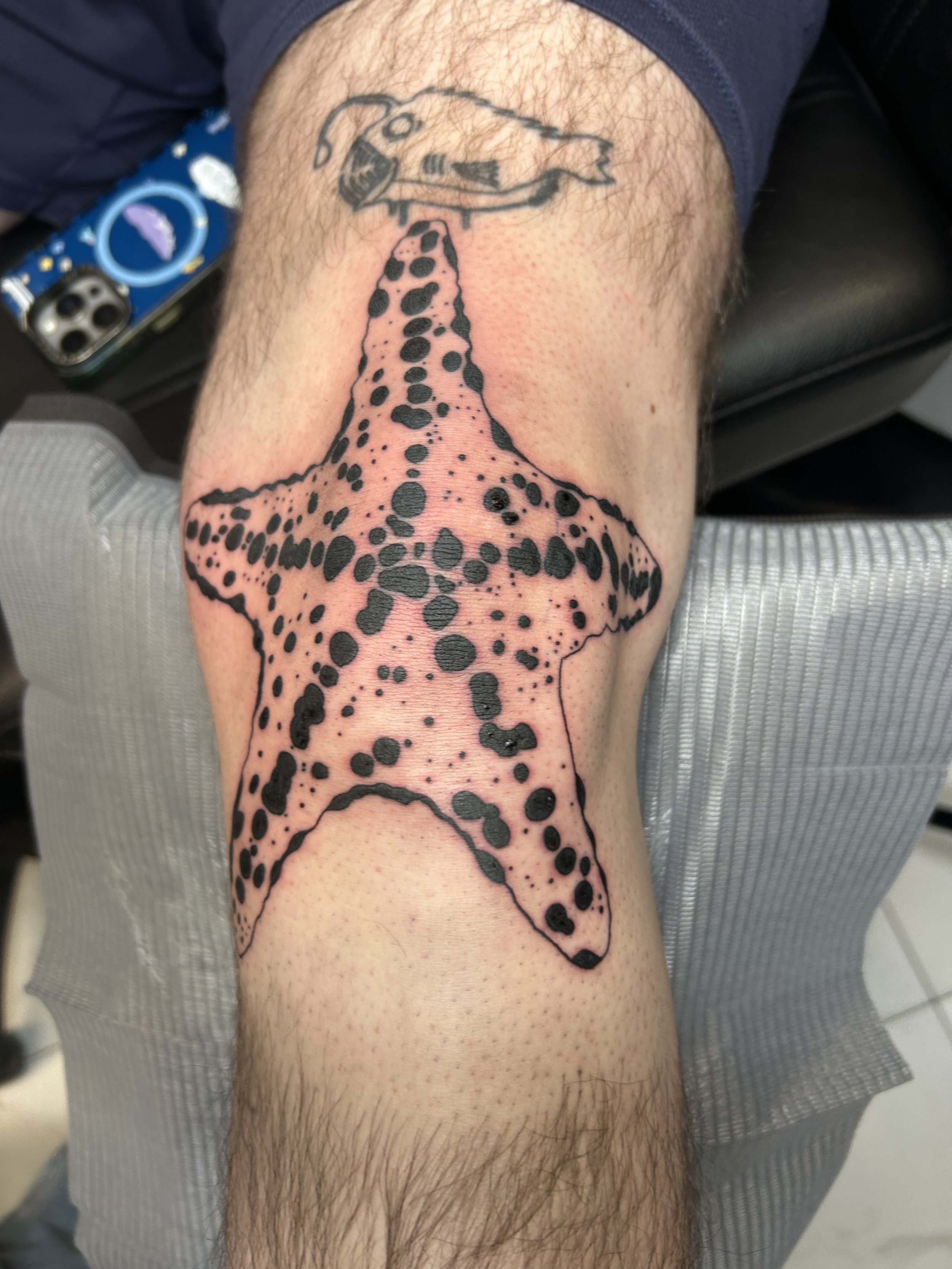 Tattoo of a starfish with a dotted pattern on a person's forearm.