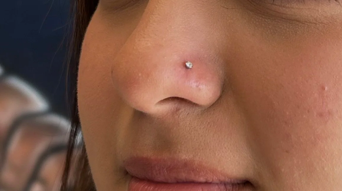 Close-up of a woman's nose with a nose stud and part of her lips visible.