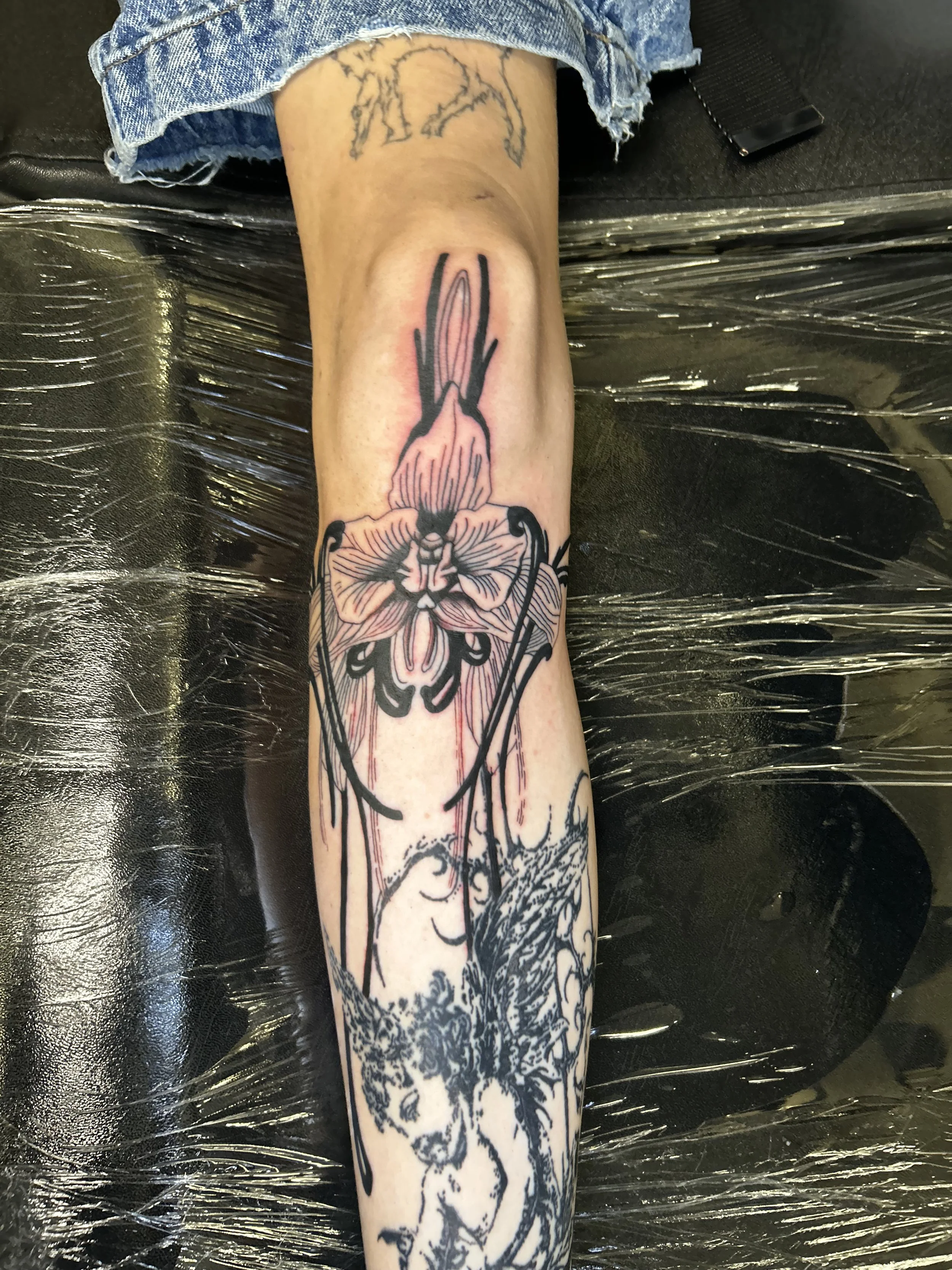 Tattoo of a woman and a flower on person's leg.