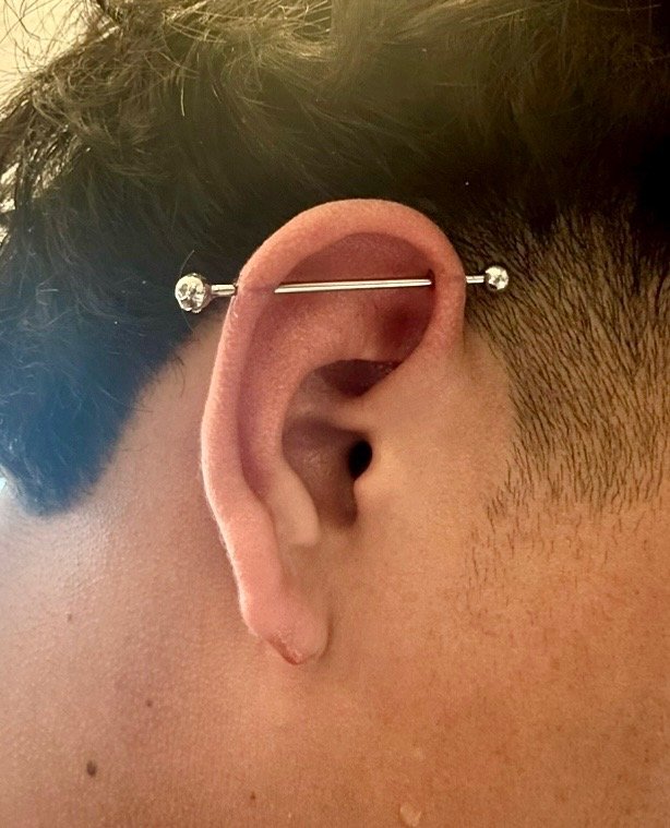 Close-up of a person's ear with a vertical barbell piercing.