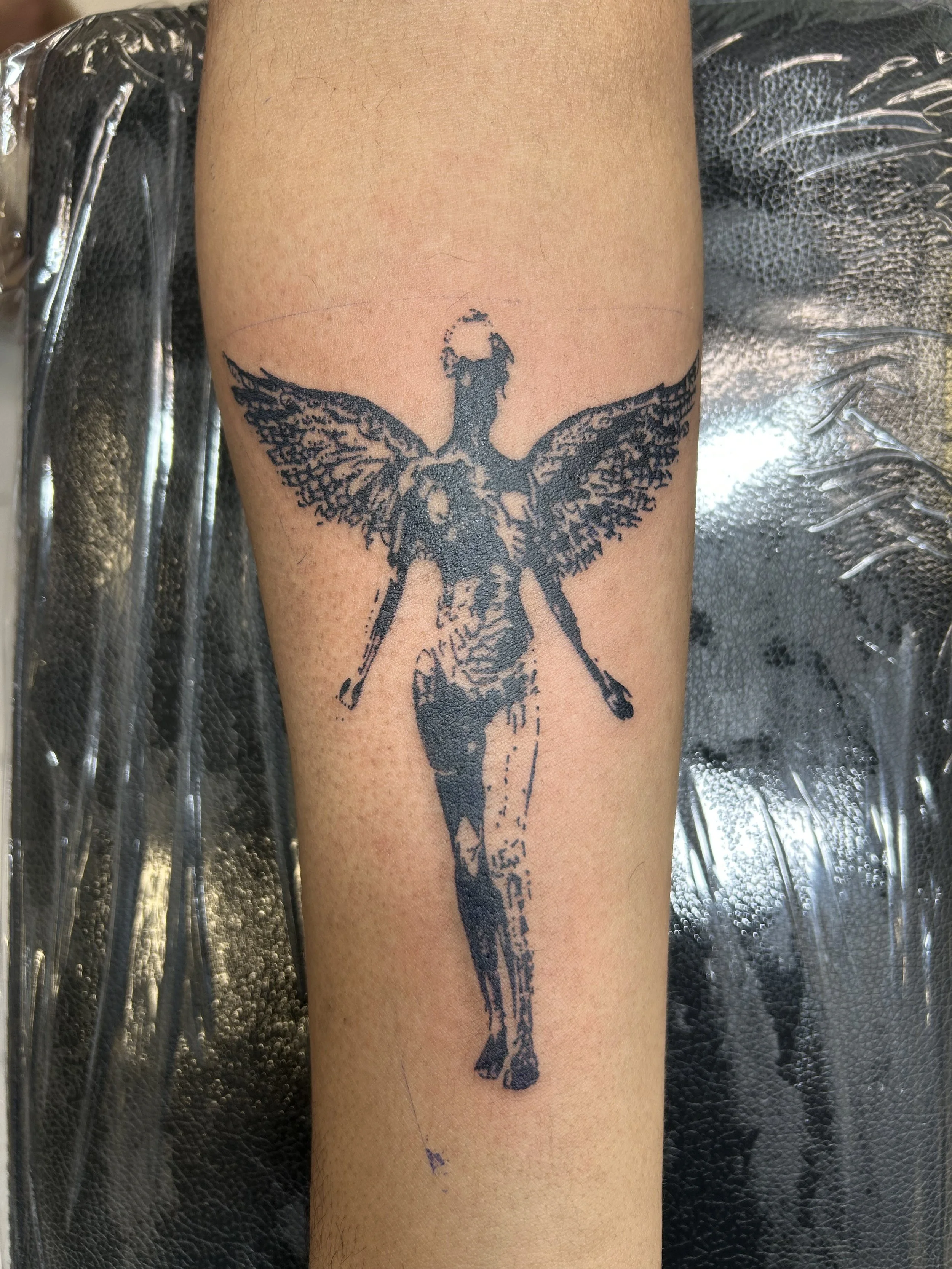 Tattoo of a fairy with butterfly wings on a person's forearm with a dark ink design.