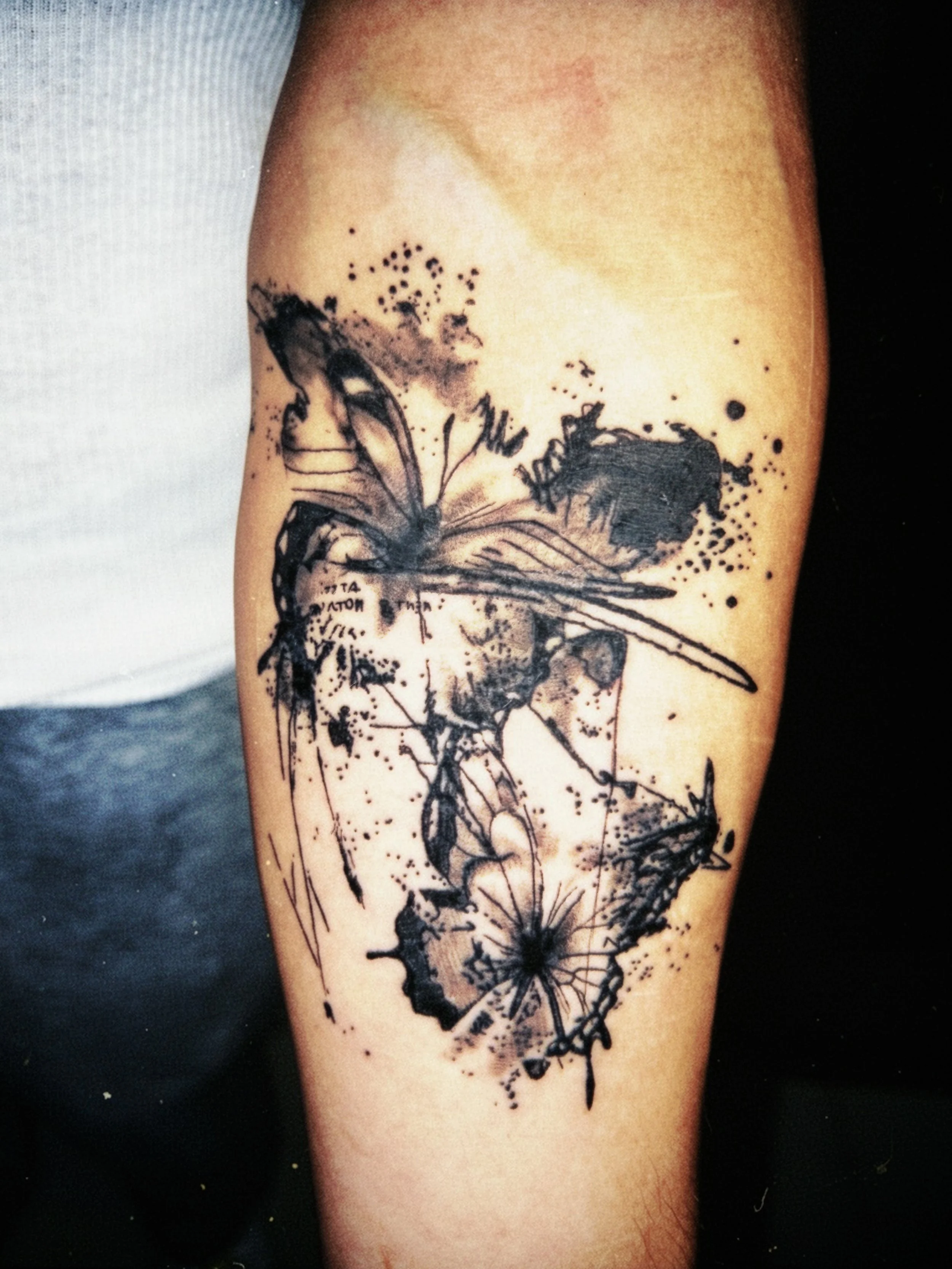 Tattoo of butterflies on a person's arm, created with black ink in a sketchy, watercolor style.