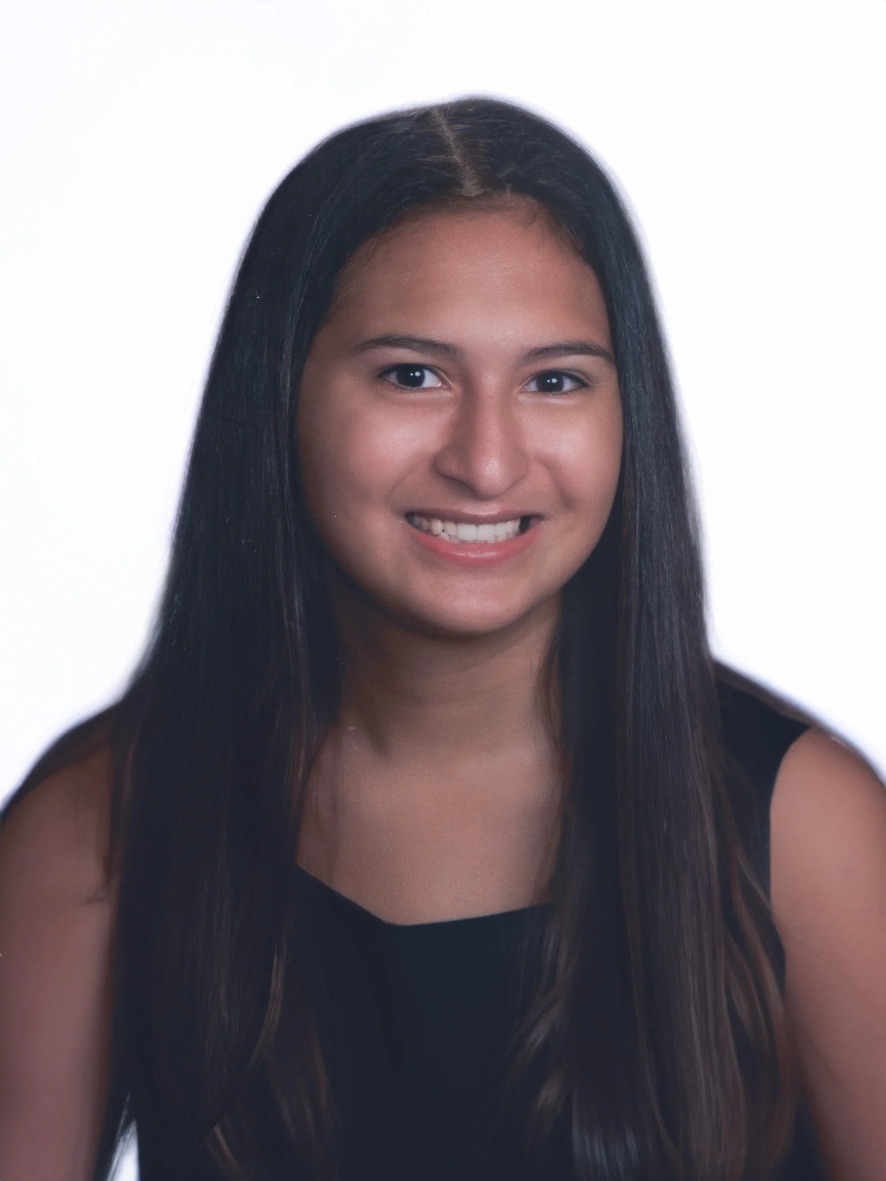 A young woman with long dark hair and a wide smile wearing a black top, against a white background.
