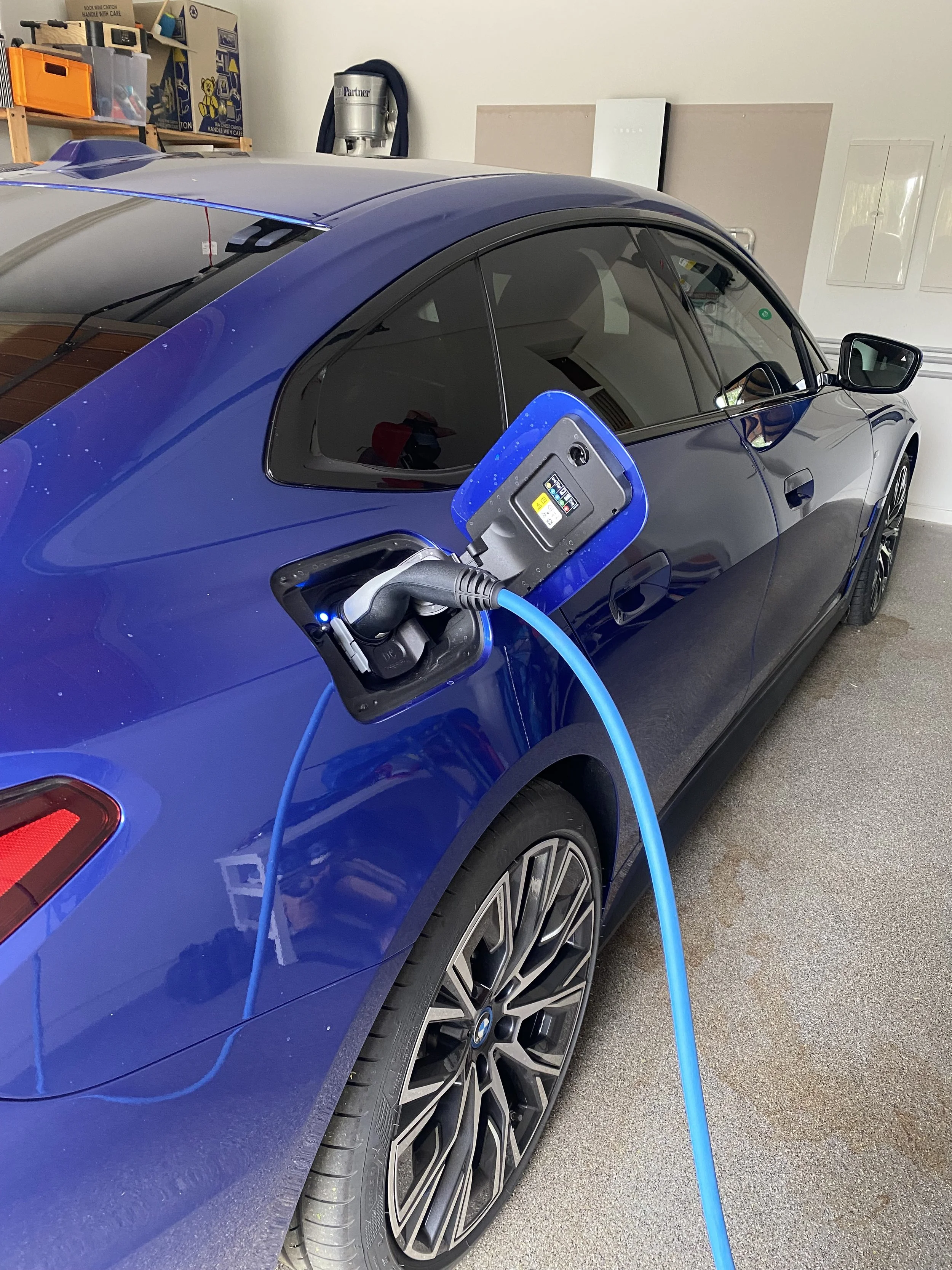 A blue electric car being charged with a charging station in a garage.