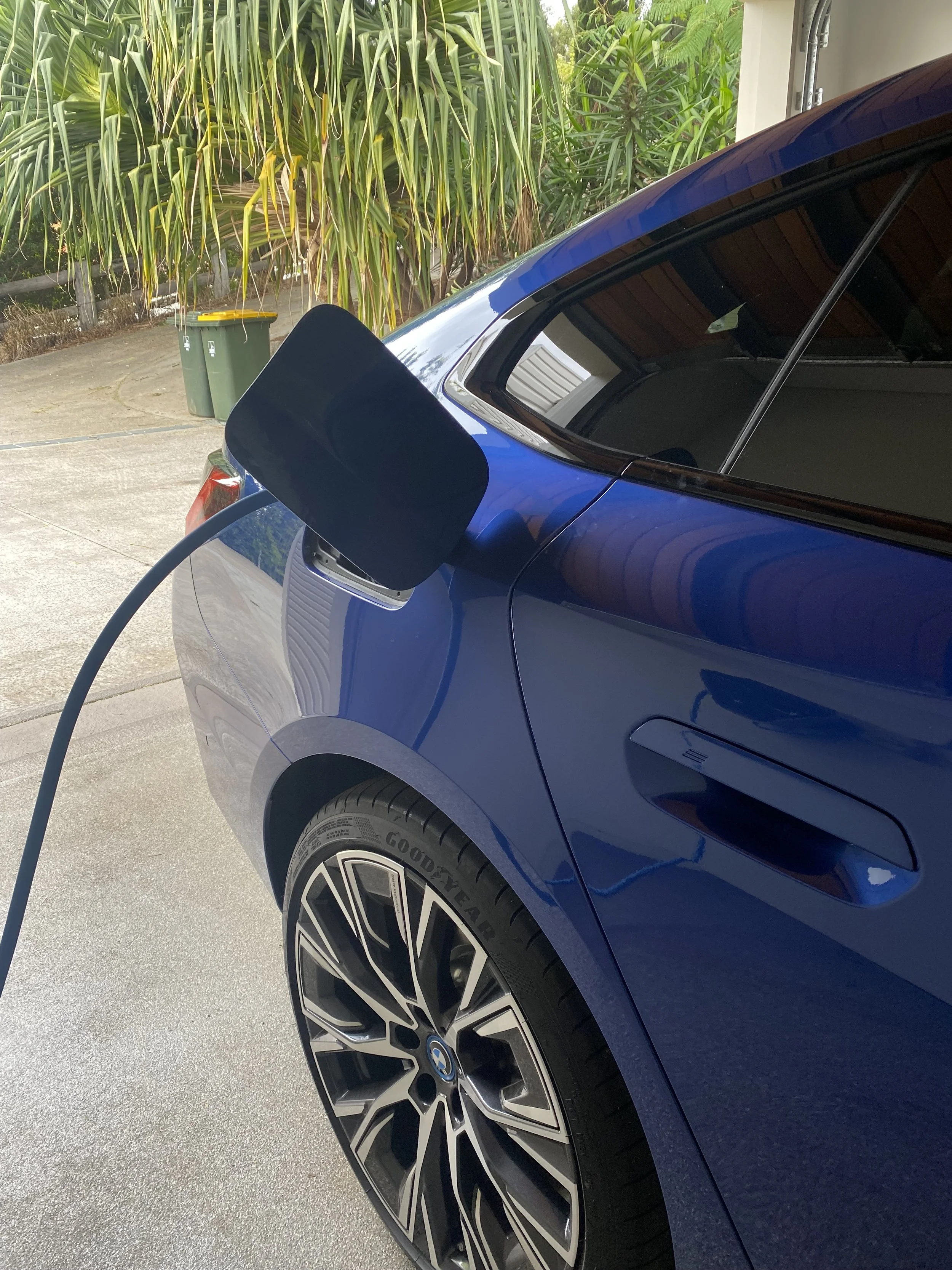 Blue electric vehicle being charging with a charging cable plugged into the port on the side of the car