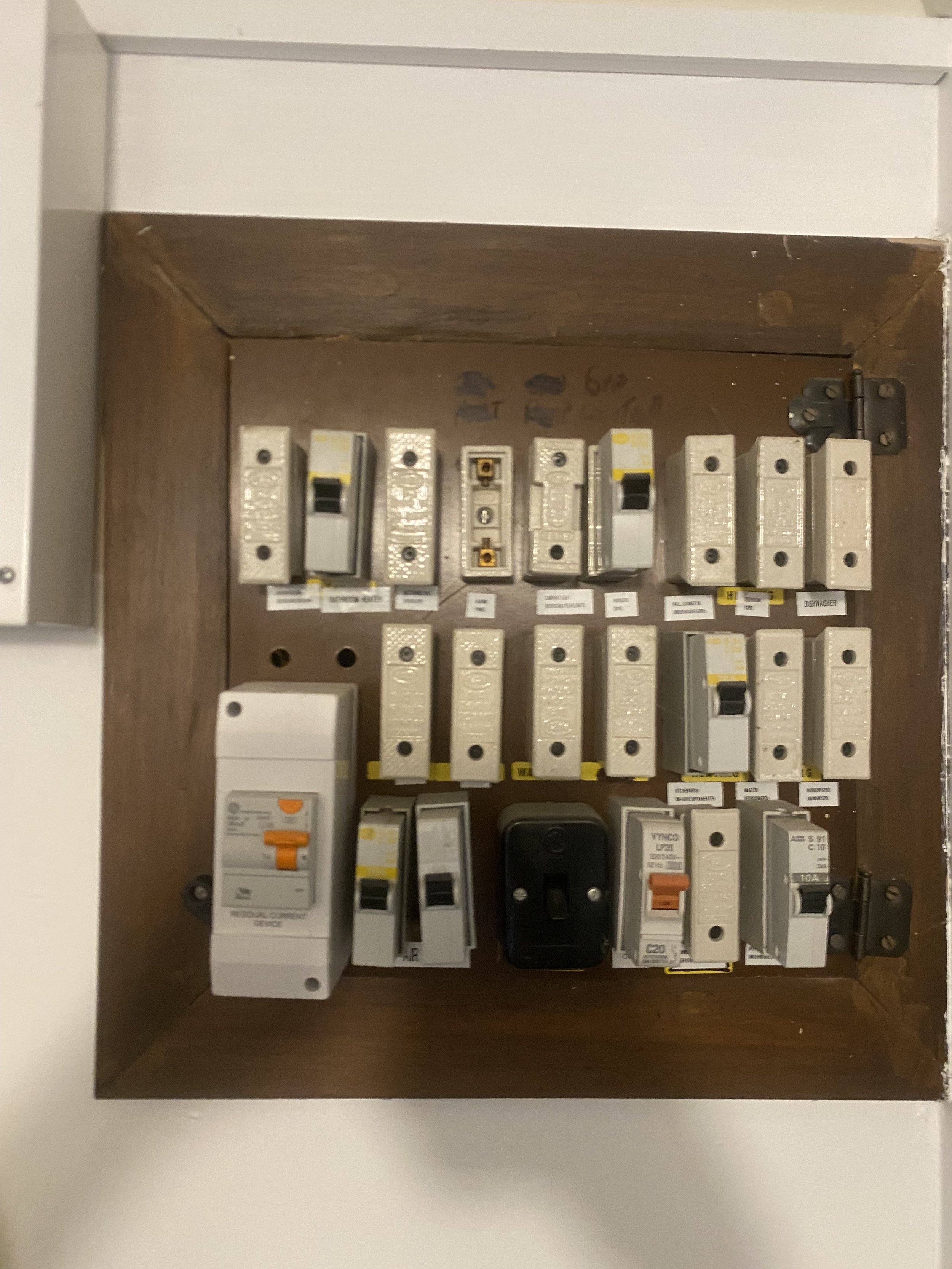 Electrical panel with circuit breakers mounted inside a wooden box.