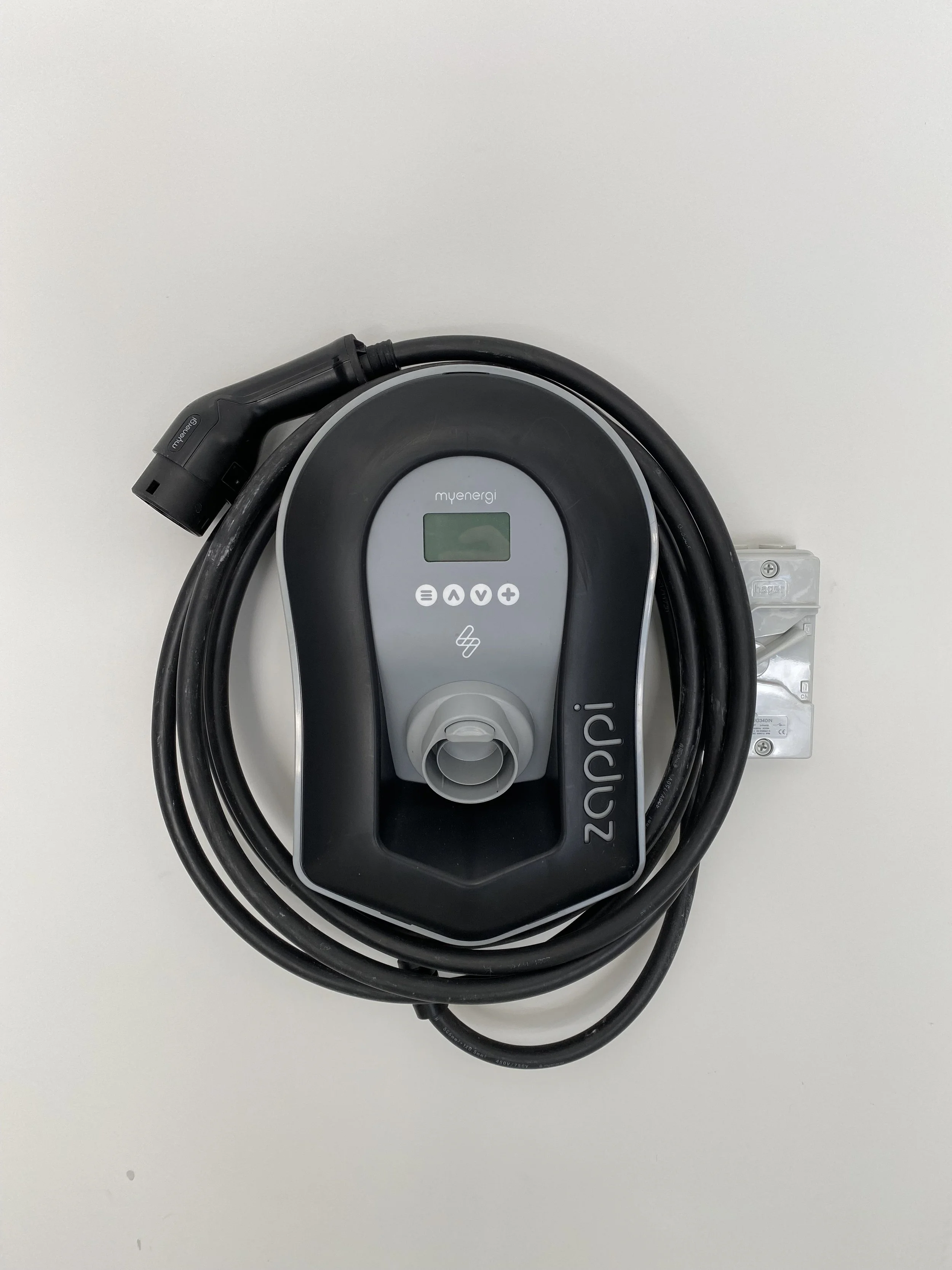 Electric vehicle charging station with cable and connector, mounted on a white wall.