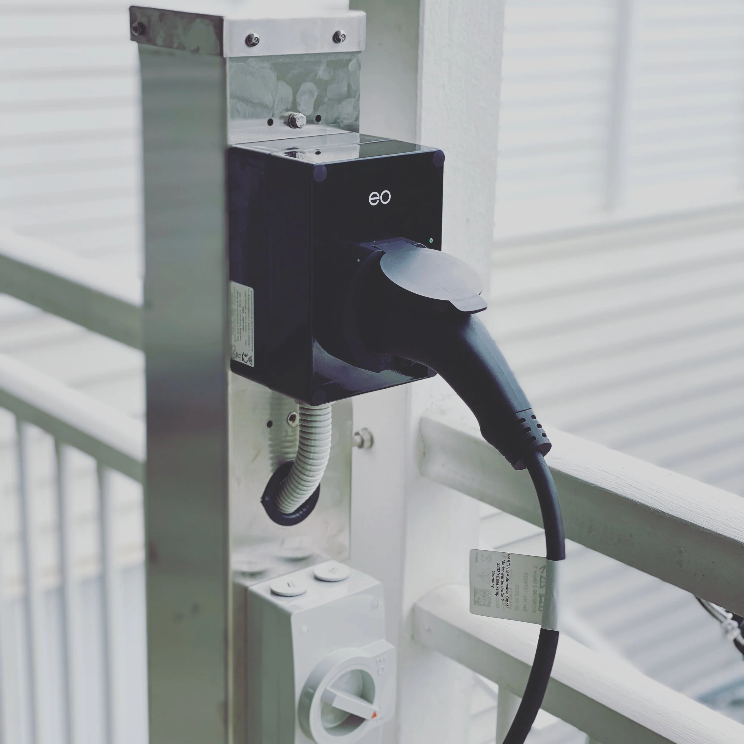 Electric vehicle charging station installed on a wall with an electrical outlet nearby.