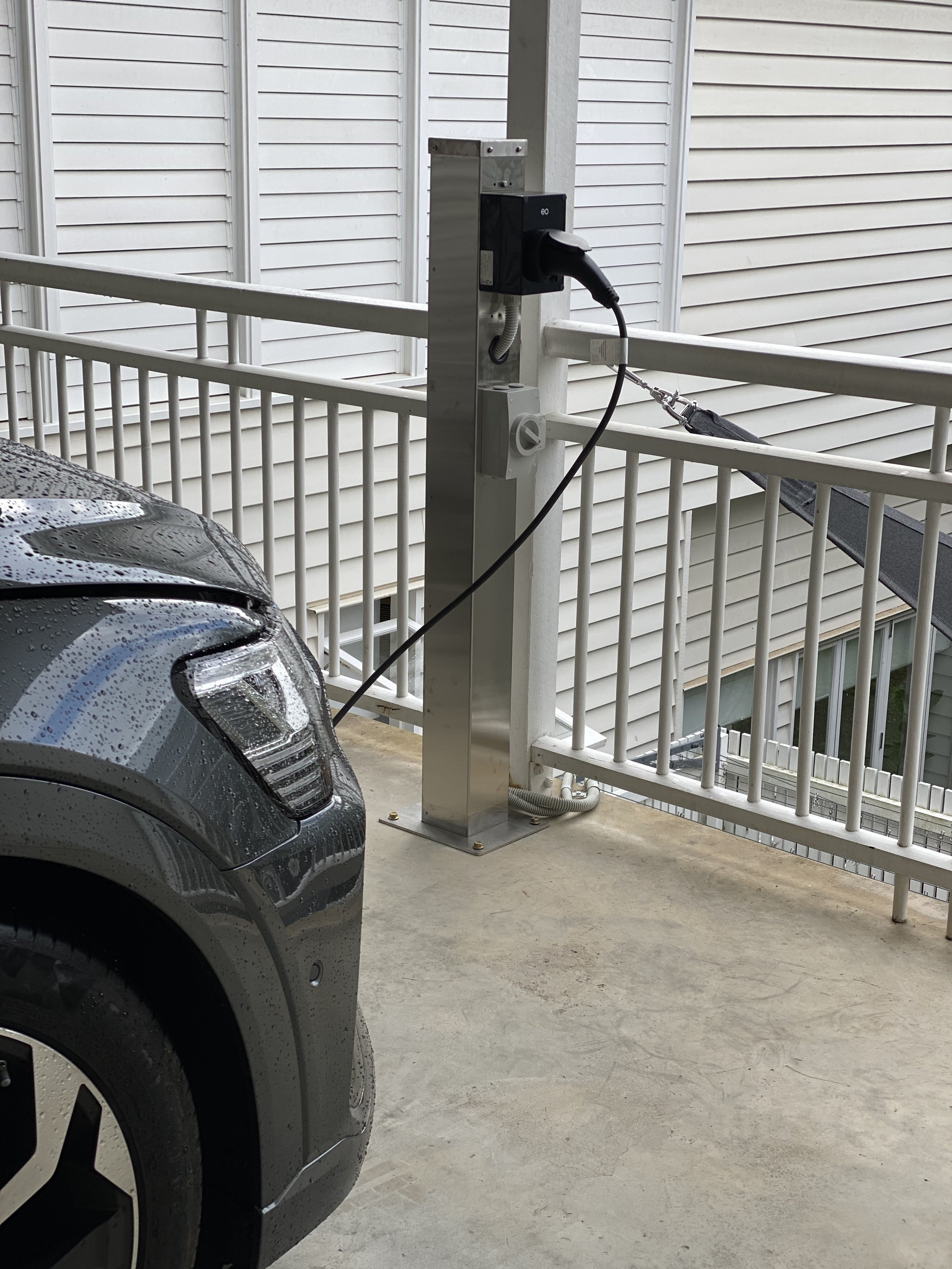 Electric vehicle charging station on a balcony or parking area with a car plugged in for charging.