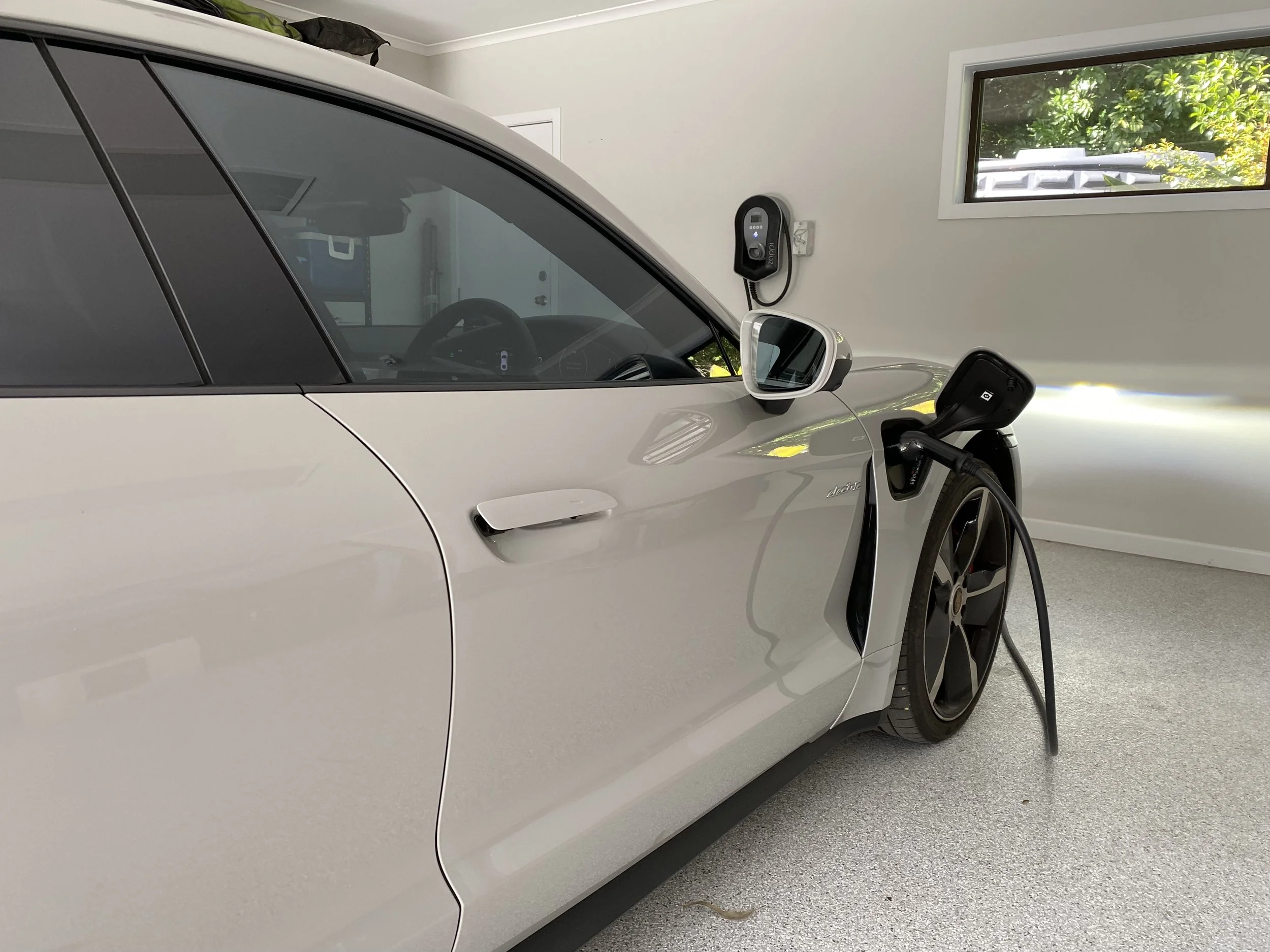 An electric car parked inside a garage, plugged into a charging station.