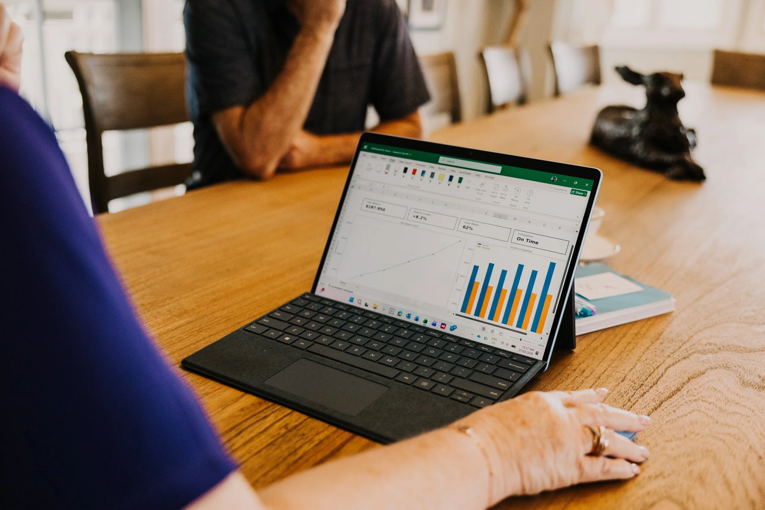 Majella meeting client in a meeting room, with a focus on a laptop displaying financial charts and graphs.