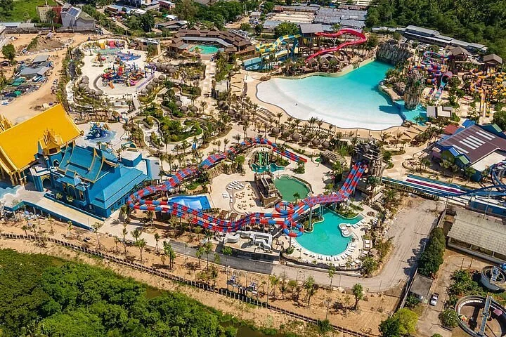 Aerial view of a water park featuring multiple water slides, pools, and recreational areas surrounded by trees and buildings.